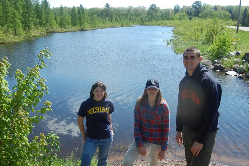 Two female and a male researcher standing together in front of a lake