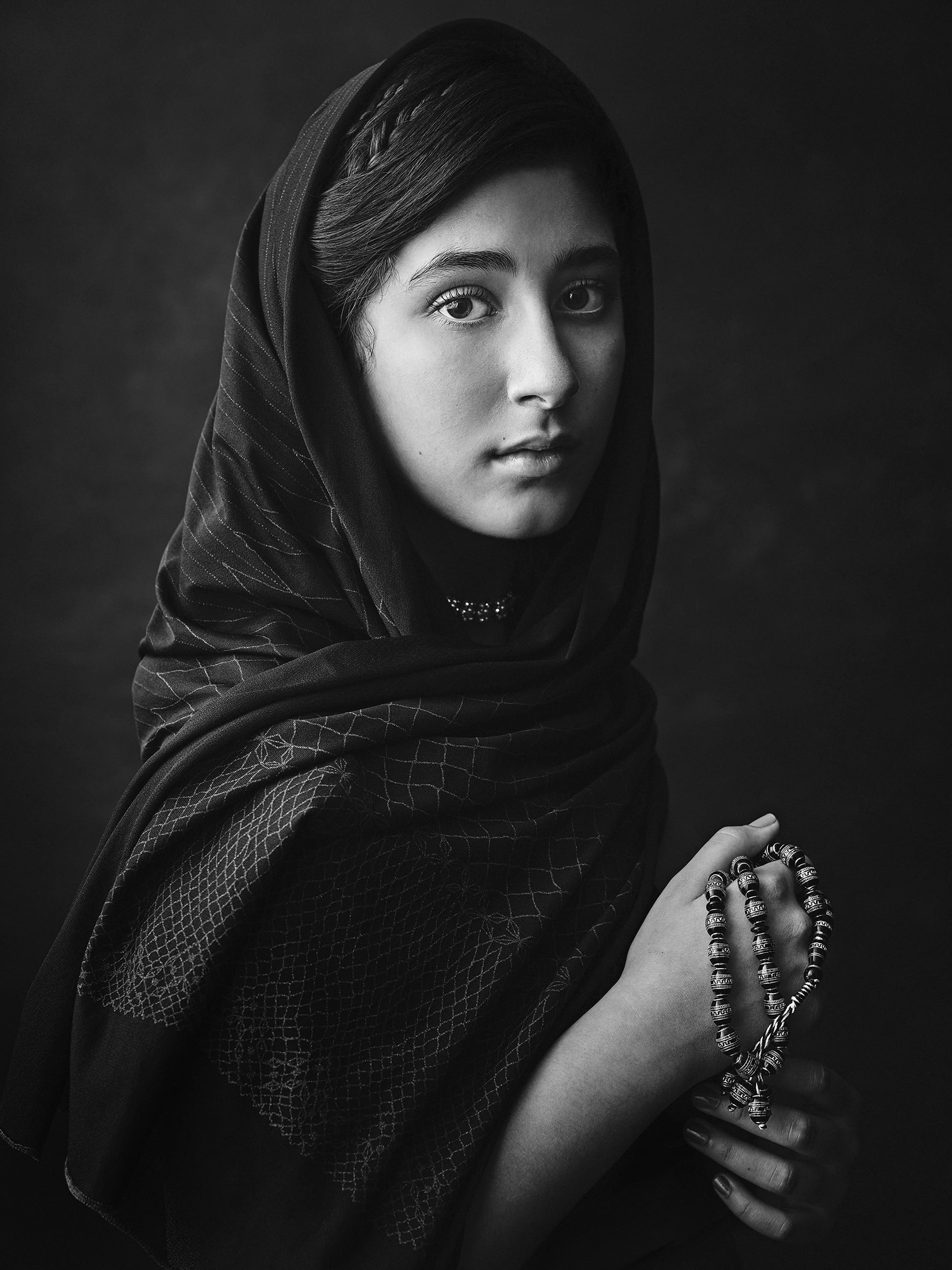 Black and white fine art portrait of a young lady holding her prayer beads