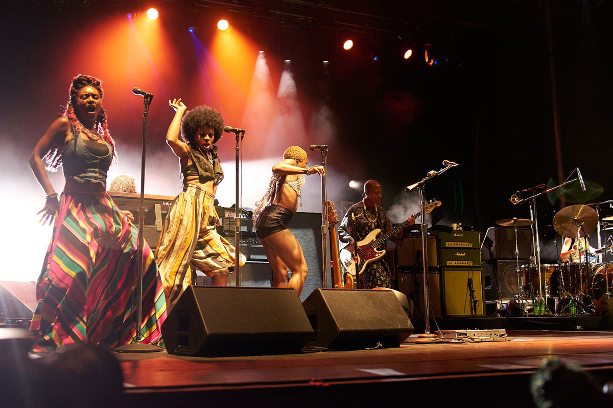 Live concert performance with colorful lighting, musicians, and singers on stage.
