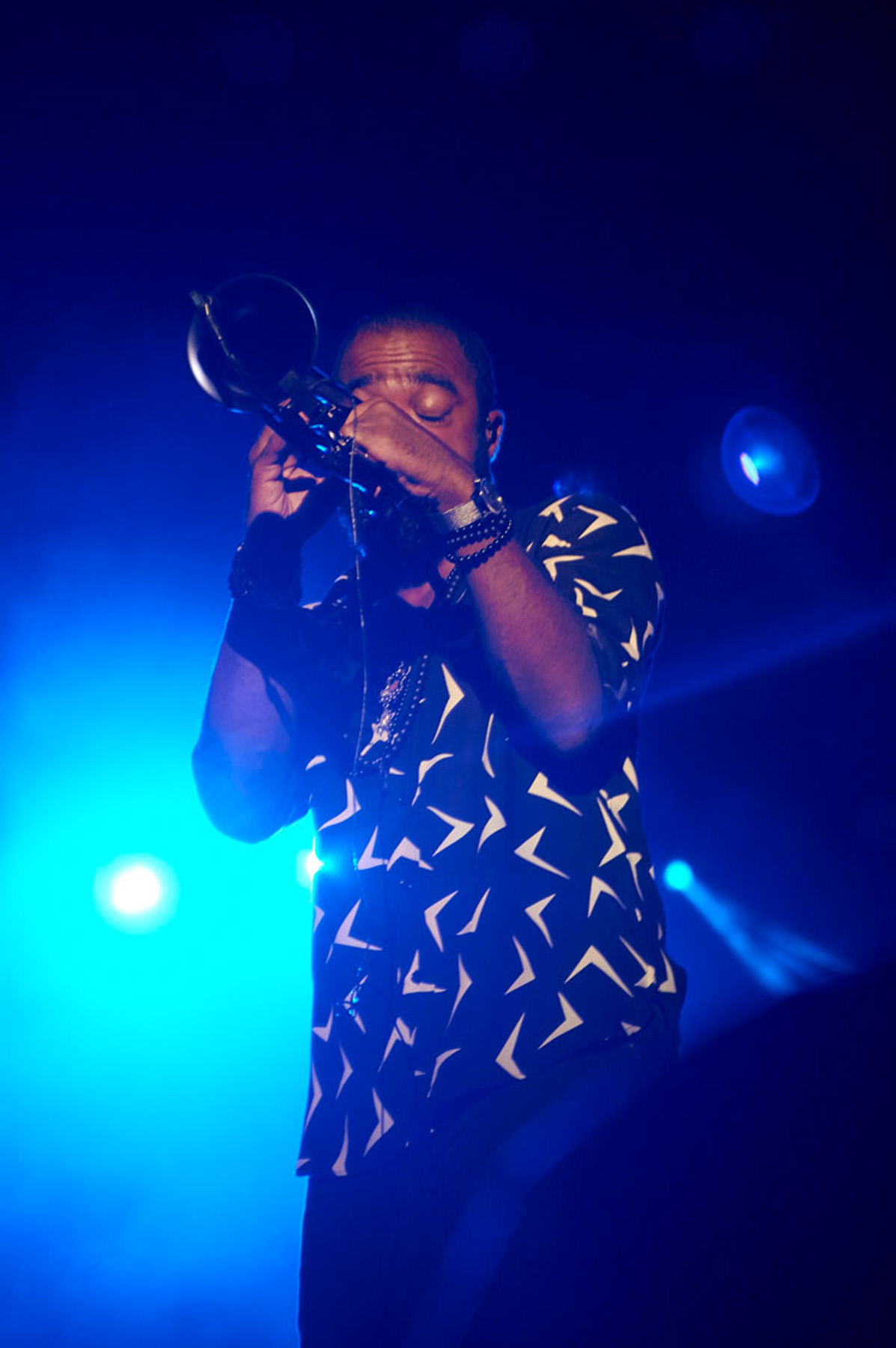 Musician playing a wind instrument under blue stage lights.