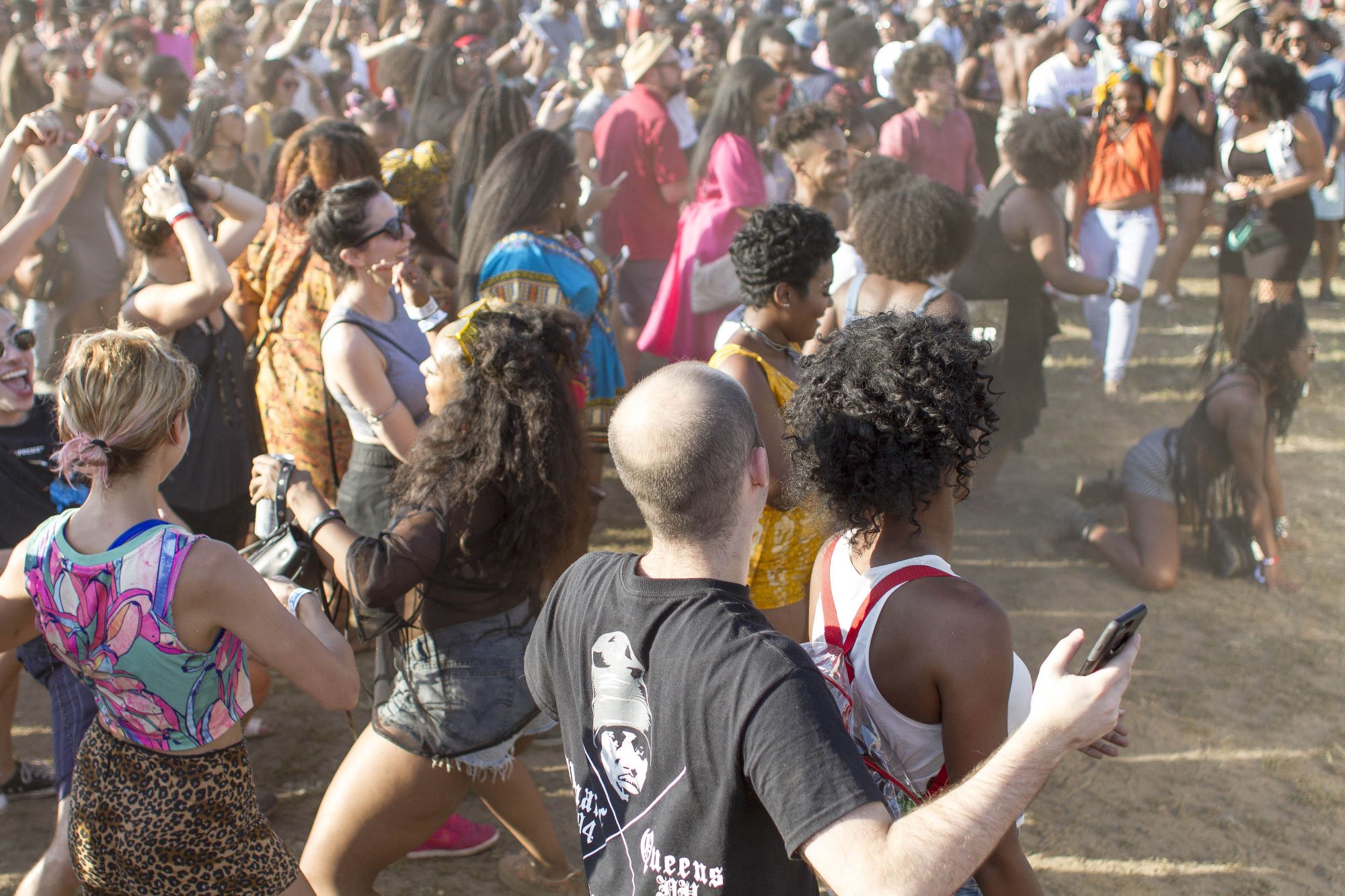 Crowd of people dancing at an outdoor music festival.