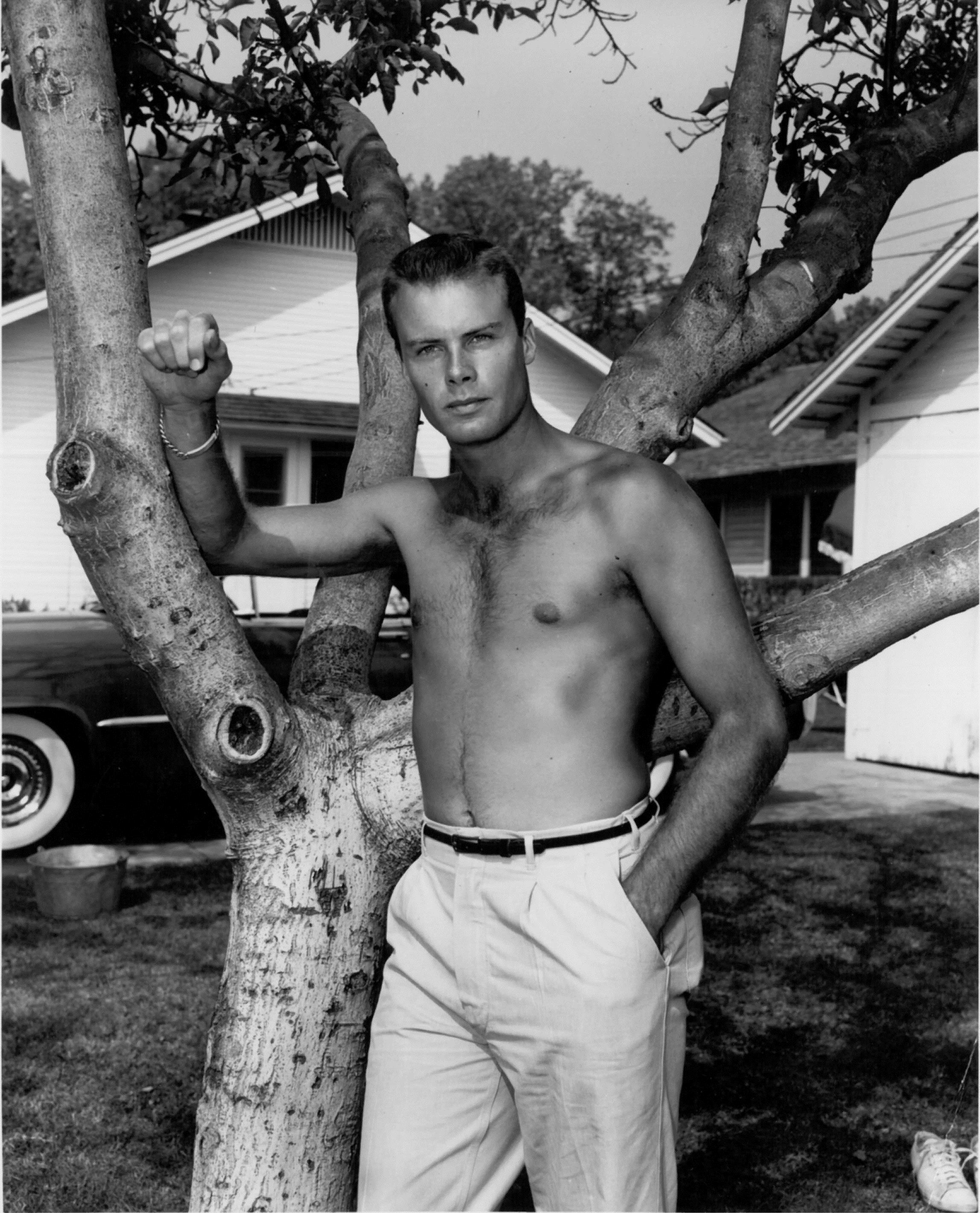  212, backyard. This early “beefcake” photo appeared in “Sigh Guy,”  Movies , Aug. 1954, c. 1953, before or after  The Caine Mutiny  shooting. In the background is Bob’s red Lincoln. Another photo in the same story shows Bob washing the whitewall tir