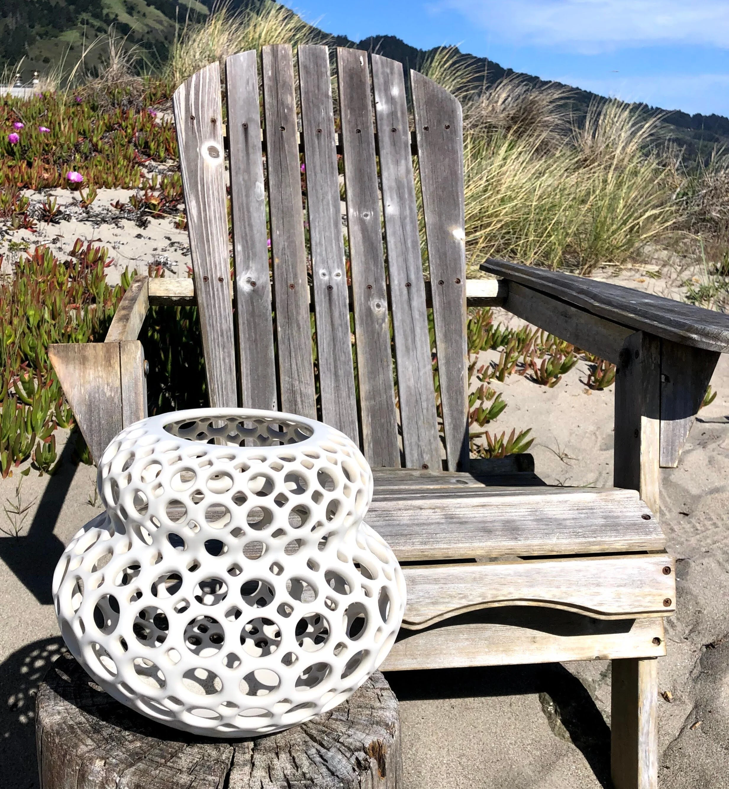 Babette tabletop sculpture, part of in Femme Collection, in white by Lynne Meade sits in front of weathered wood Adirondack chair.