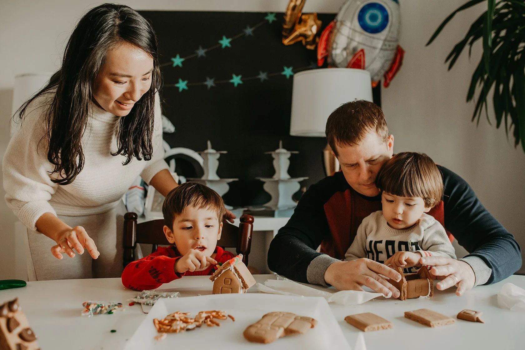 Family making a gingerbread house during a photo session