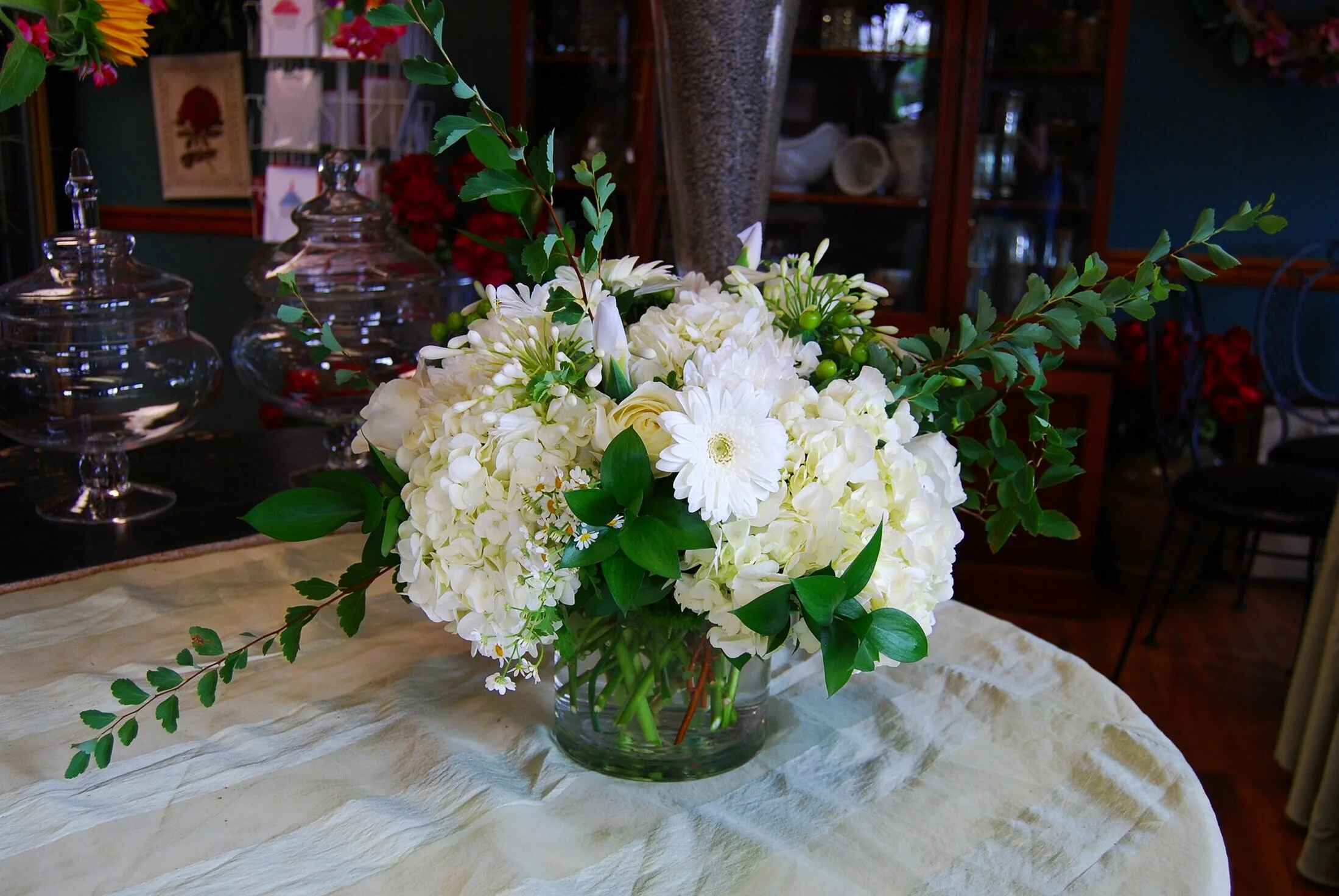 All white sympathy flower arrangement designed with hydrangea, gerbera daisies and roses. Simply beautiful.