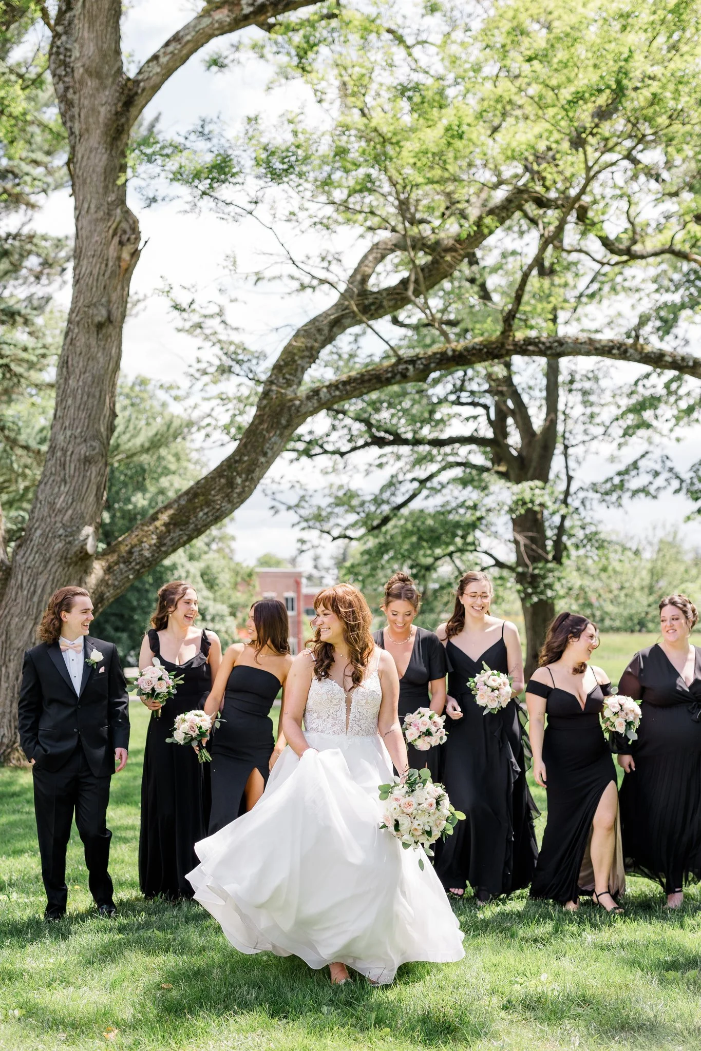 Bridesmaids walking with bridal bouquets of white and pink flowers at Ellis Preserve