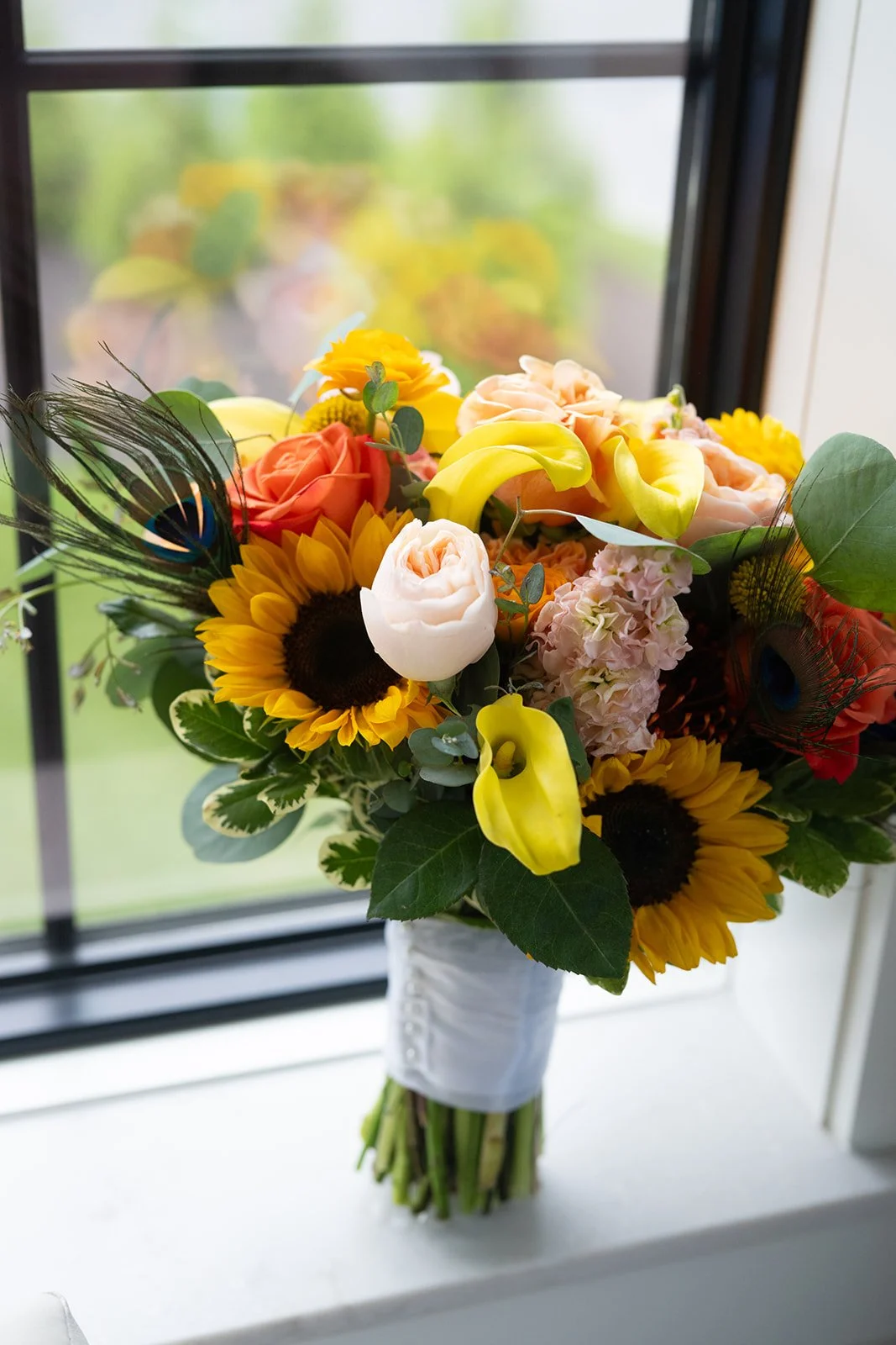 Bridal bouquet with sunflowers, cala lilies, roses and ostrich feathers
