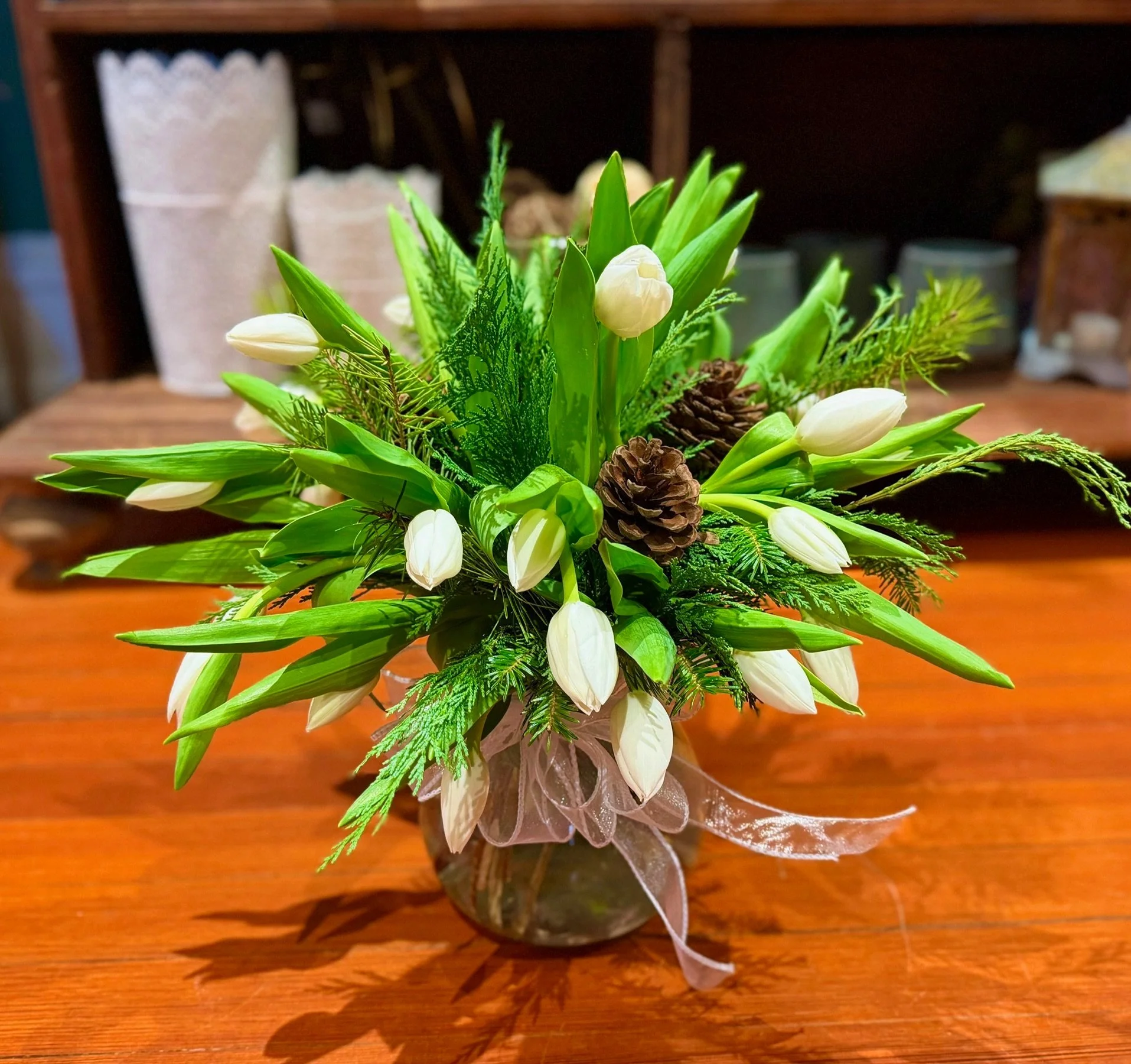White Tulips with wintergreens, pinecones and a bow