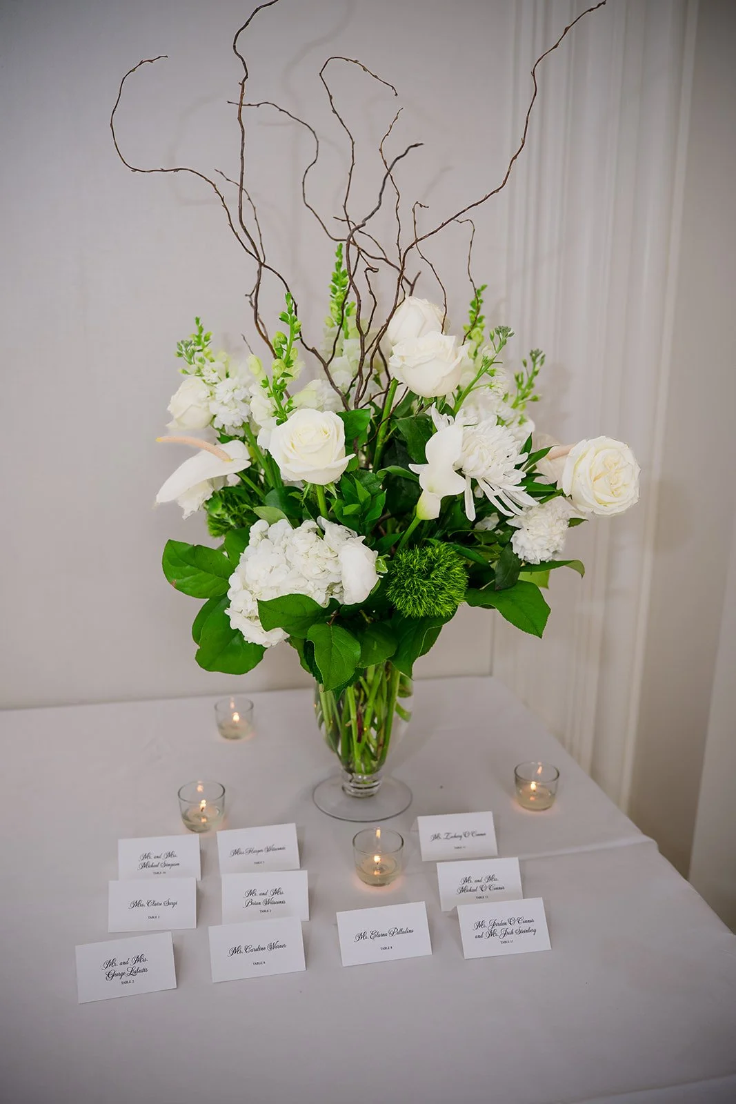 White calla lilies, white roses, white hydrangea, white anthurium and white snapdragon with curly willow and dianthus