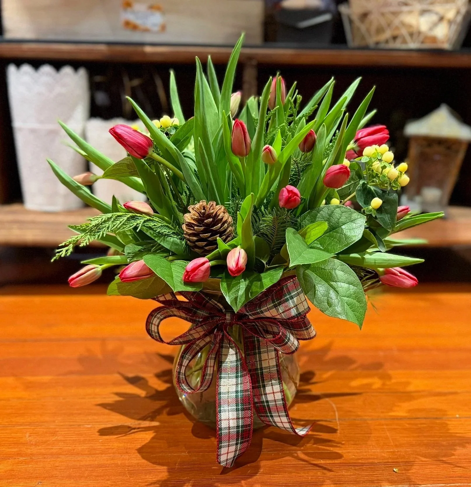 Red Tulips with wintergreens, pinecones and a holiday bow