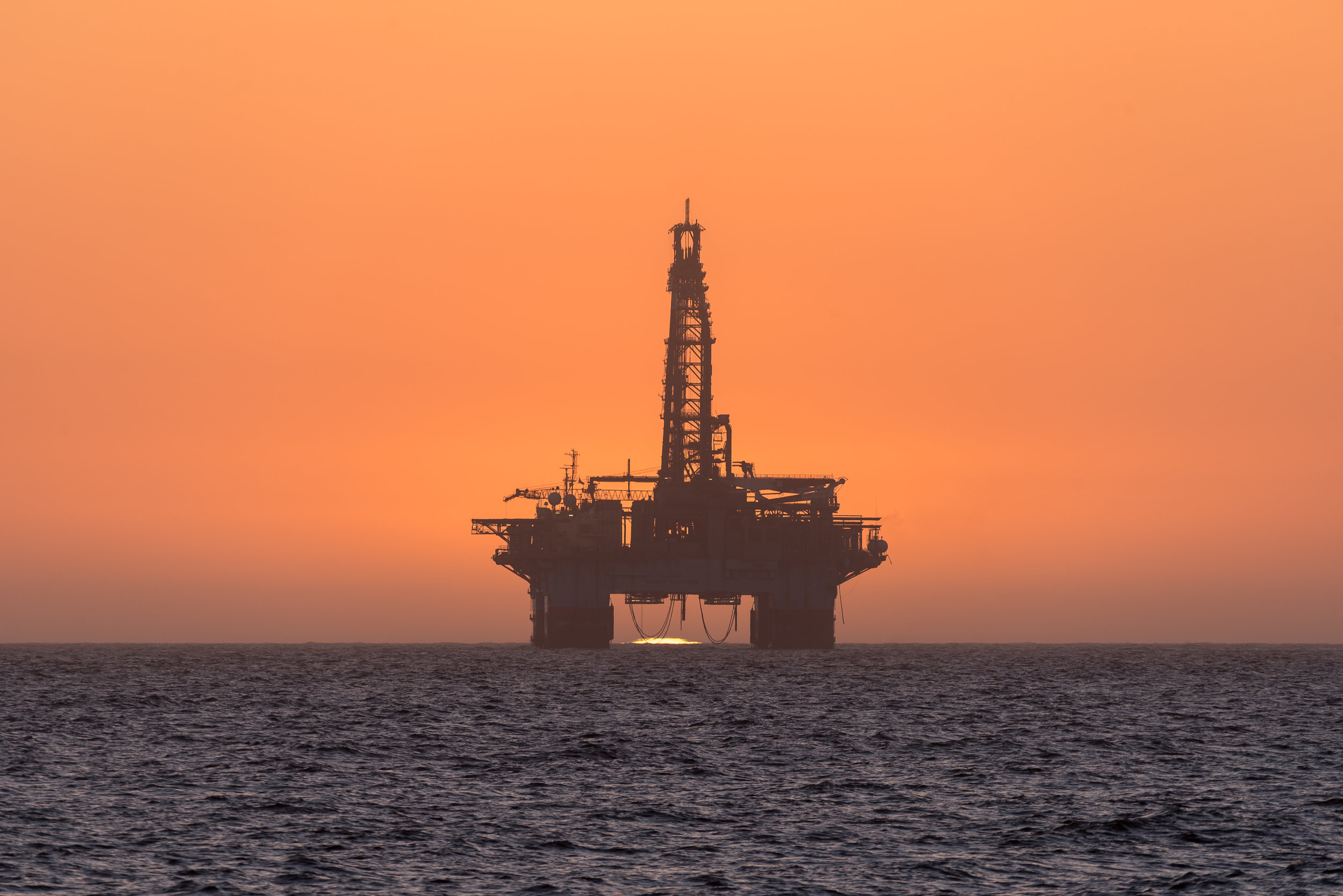 sun-setting-behind-oil-drilling-platform-at-PABDJBR.jpg