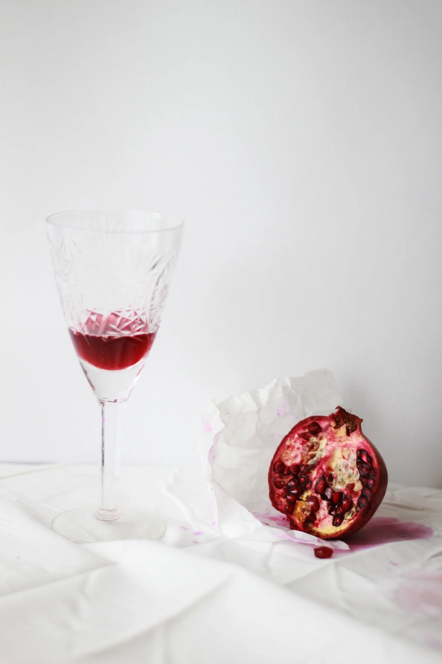 A pomegranate fruit with a crystal glass of juice on a white background