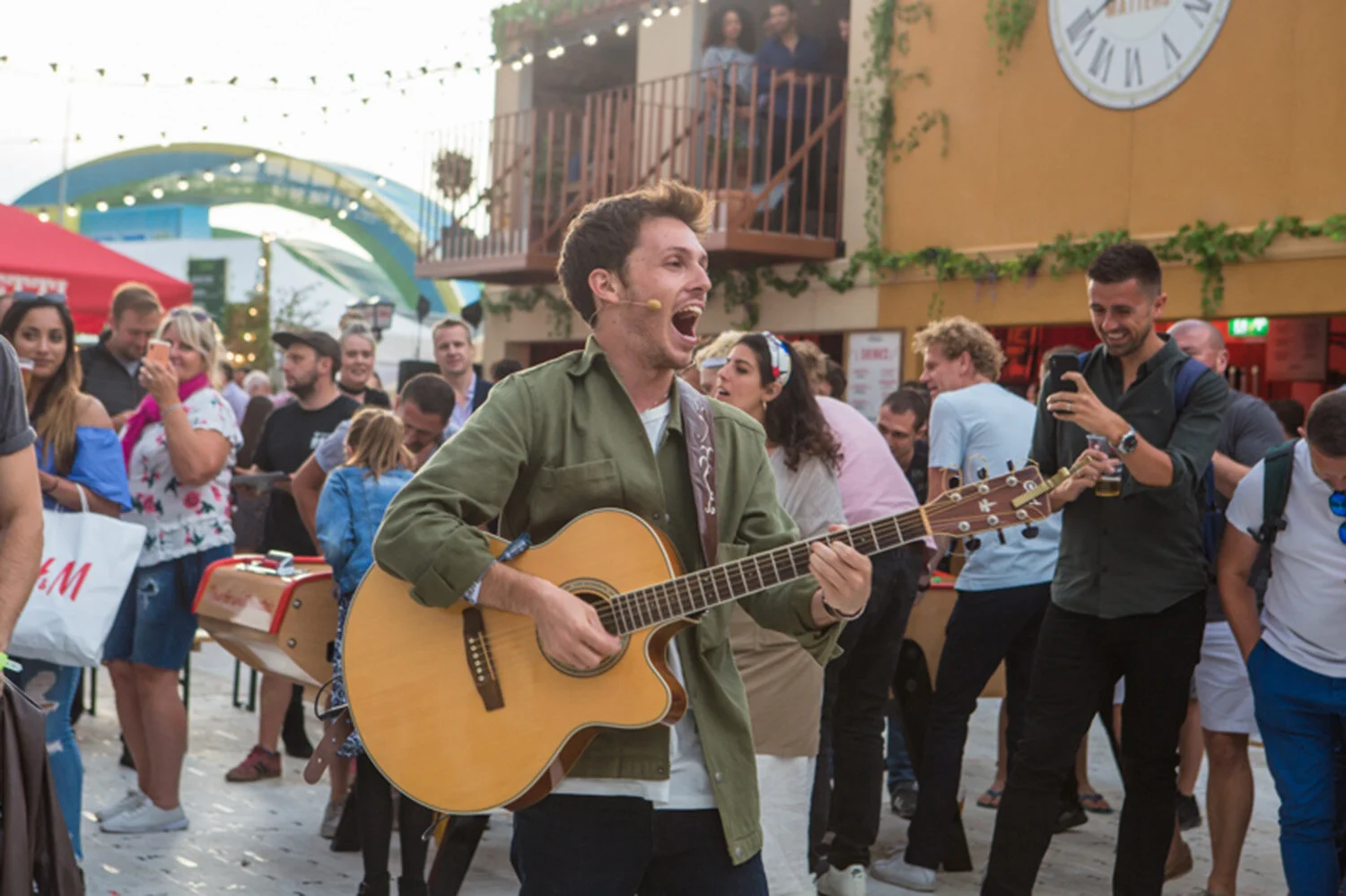 man-in-green-jacket-playing-guitar-singing-in-hyde-park-while-people-drink-beer.jpg