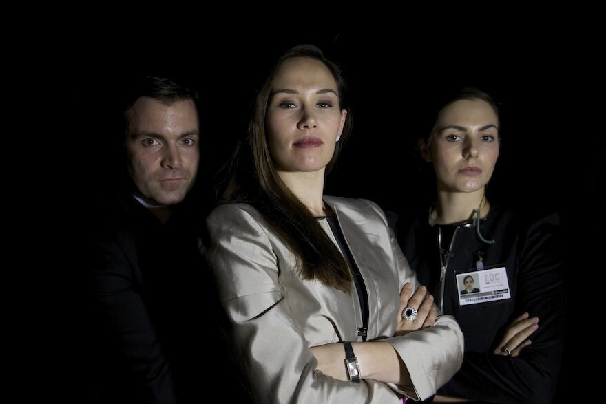  3 professionals including female boss with folded arms looking serious 