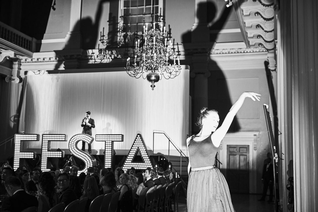  black and white image of woman dancing with her shadow projected against plush backdrop 