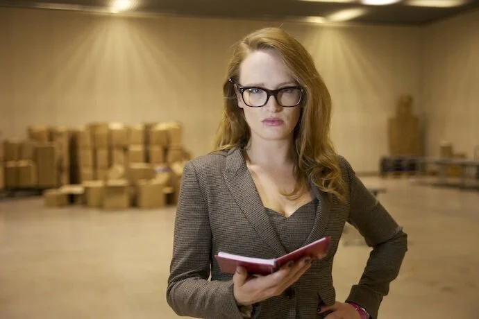 tweed+suited+woman+with+glasses+holding+a+note+book+in+warehouse+space.jpg