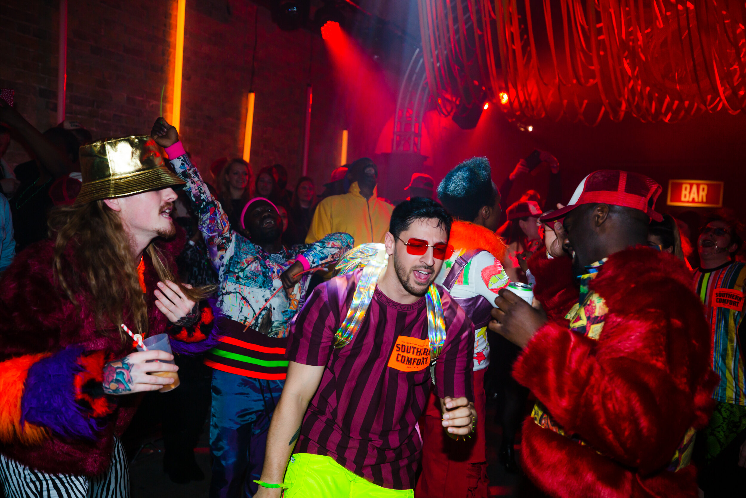  90’s inspired ravers wear fluro outfits and talk and dance on the dance floor 