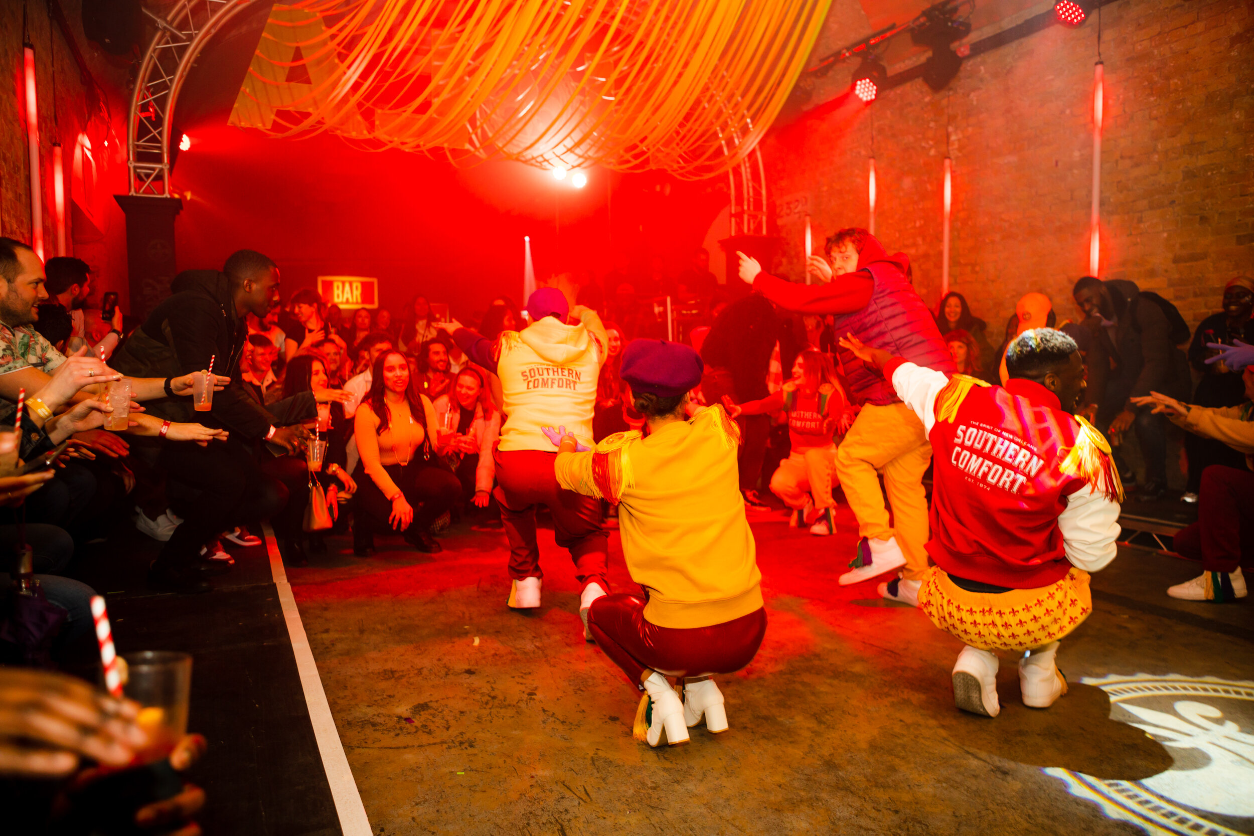  cast of actors in marching band costumes detailed with southern comfort get the audience to get down low as the hackney colliery band build up the music 