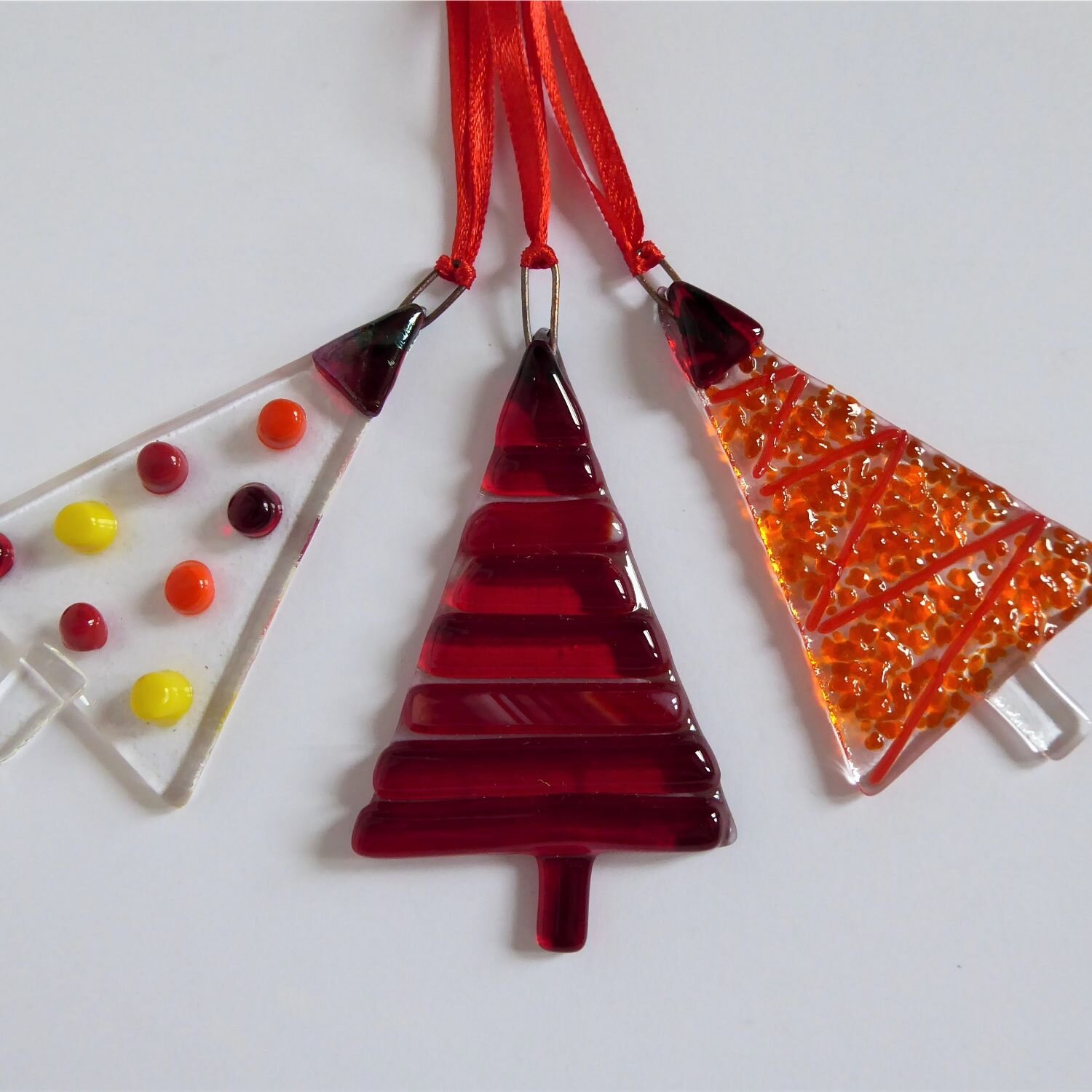  A set of three red fused glass tree-shaped Christmas decorations by Eva Glass Design 