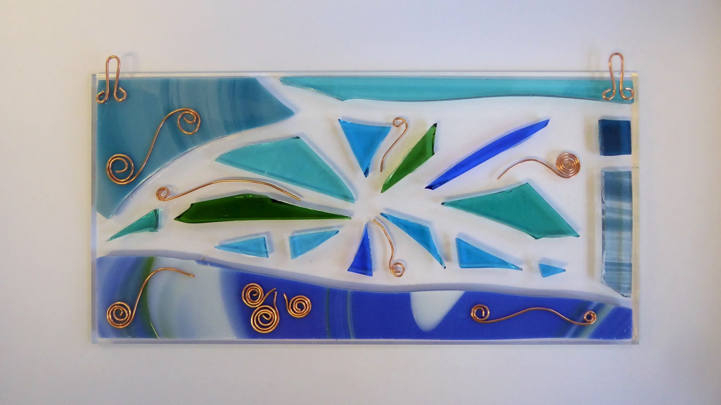 Fused glass wall panel in shades of blue and green created by Eva Glass Design.