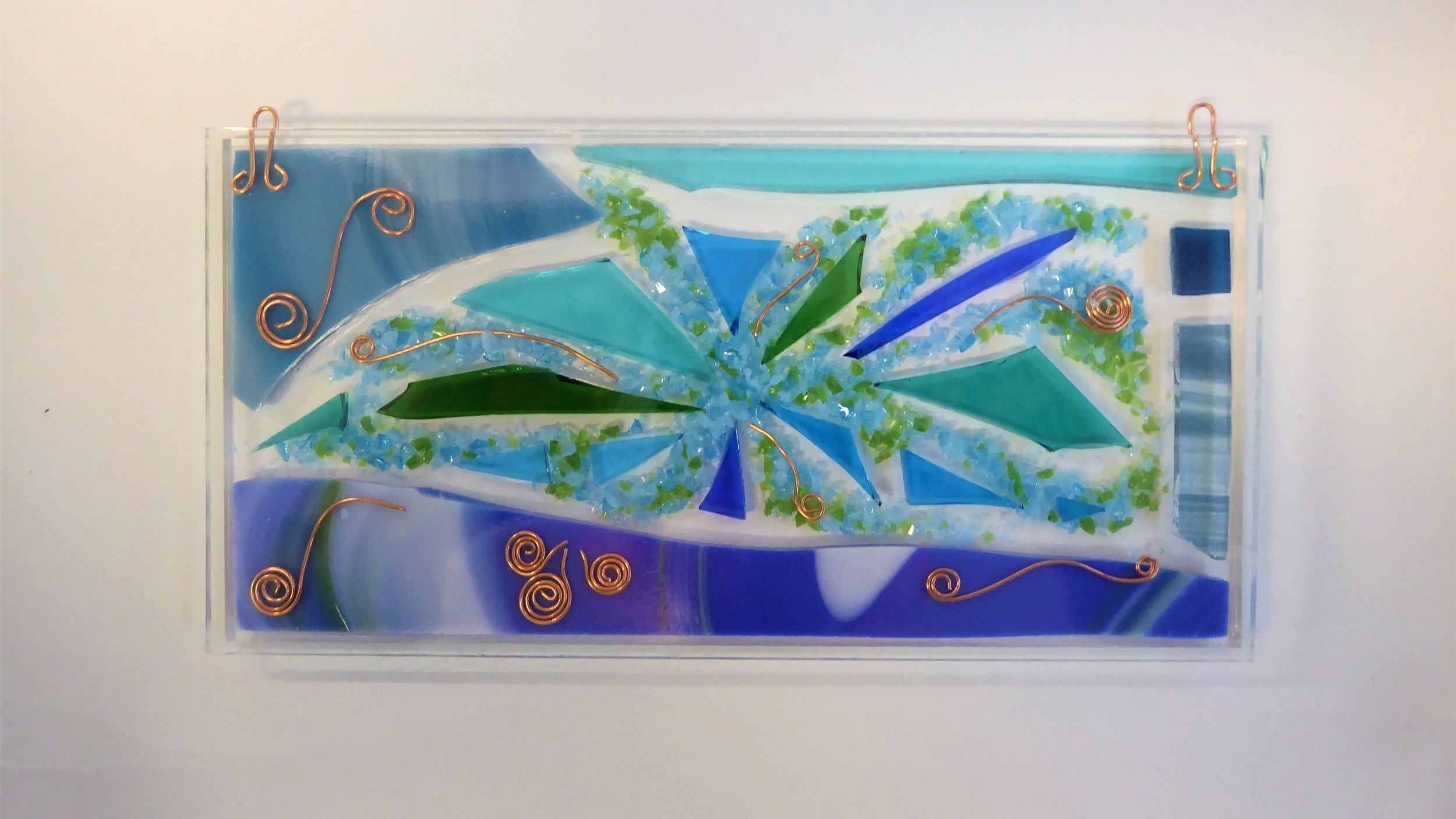 Fused glass wall panel in shades of blue and green created by Eva Glass Design.