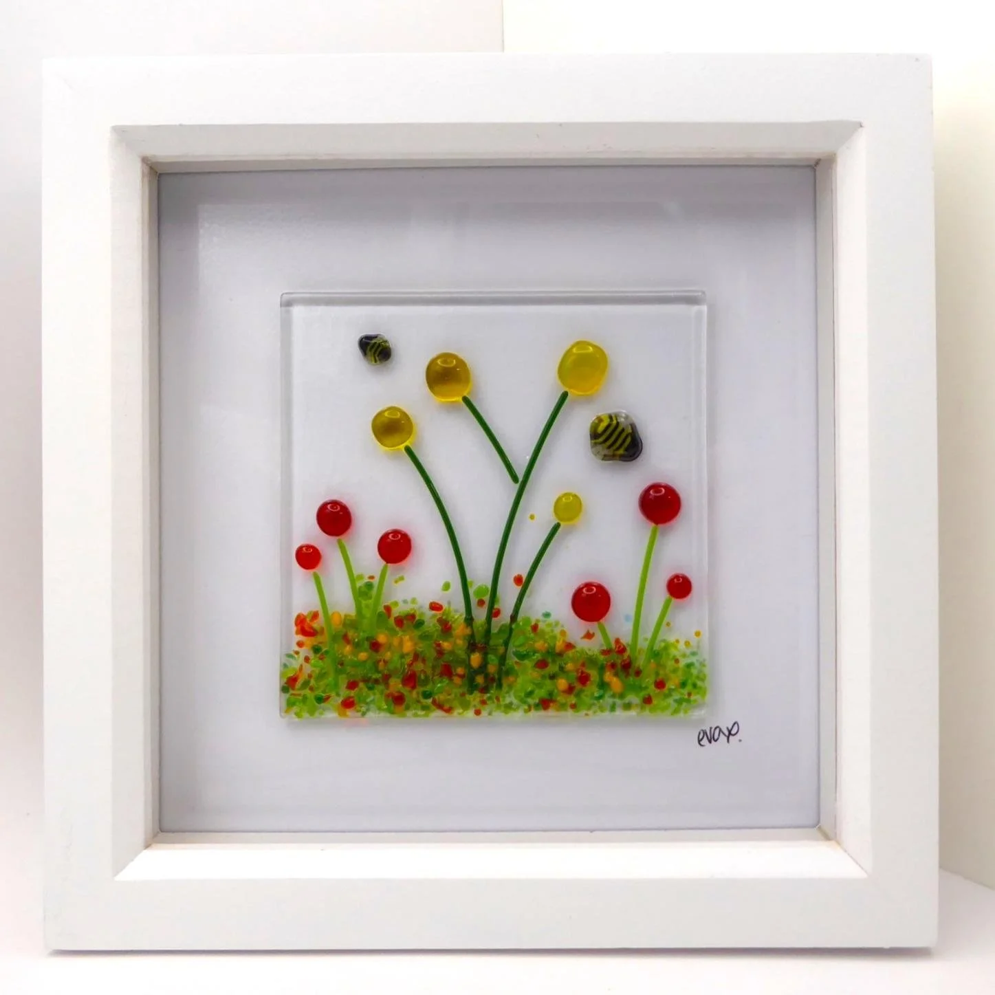  Fused glass framed wall art featuring bees flying over a wildflower meadow with orange and yellow flowers 