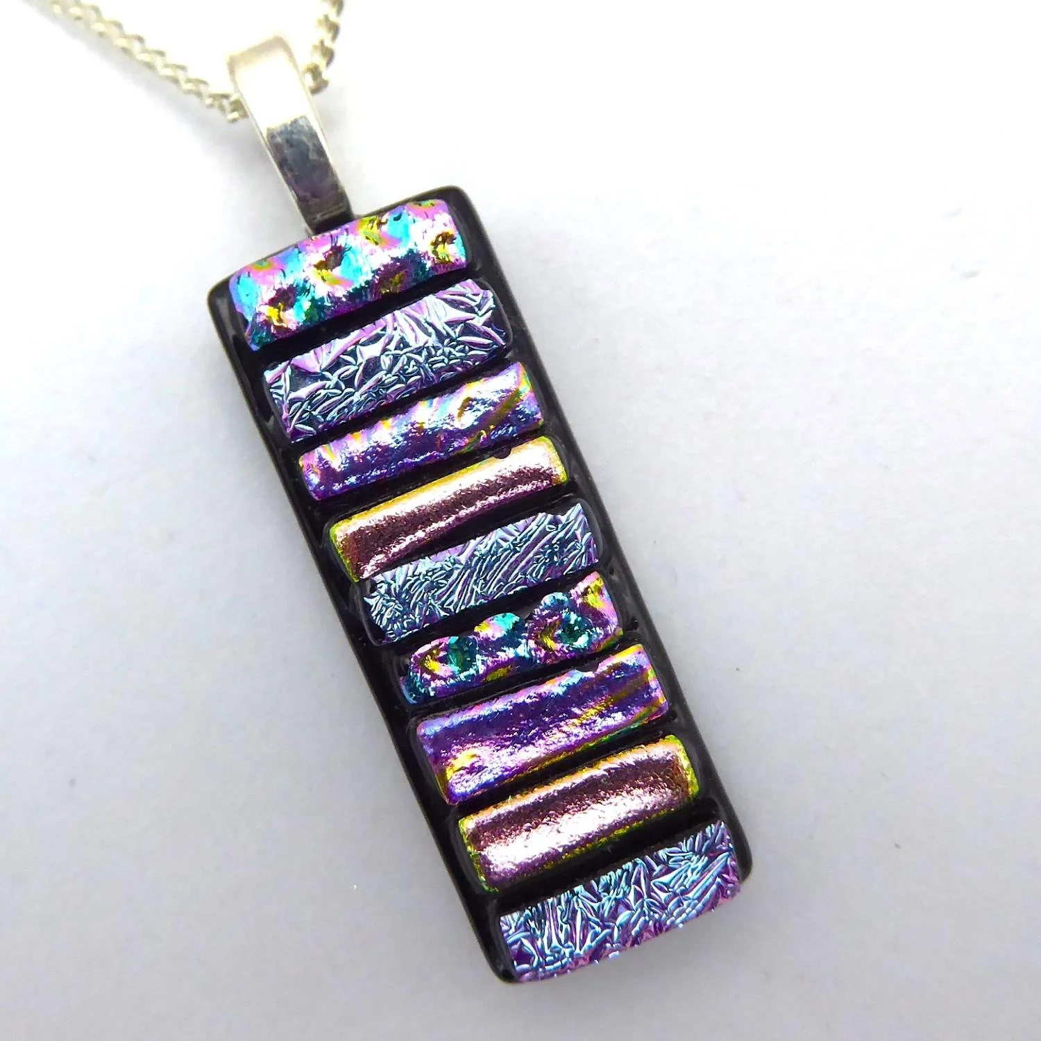  Fused glass necklace with strips of pale pink dichroic glass fused onto black glass 