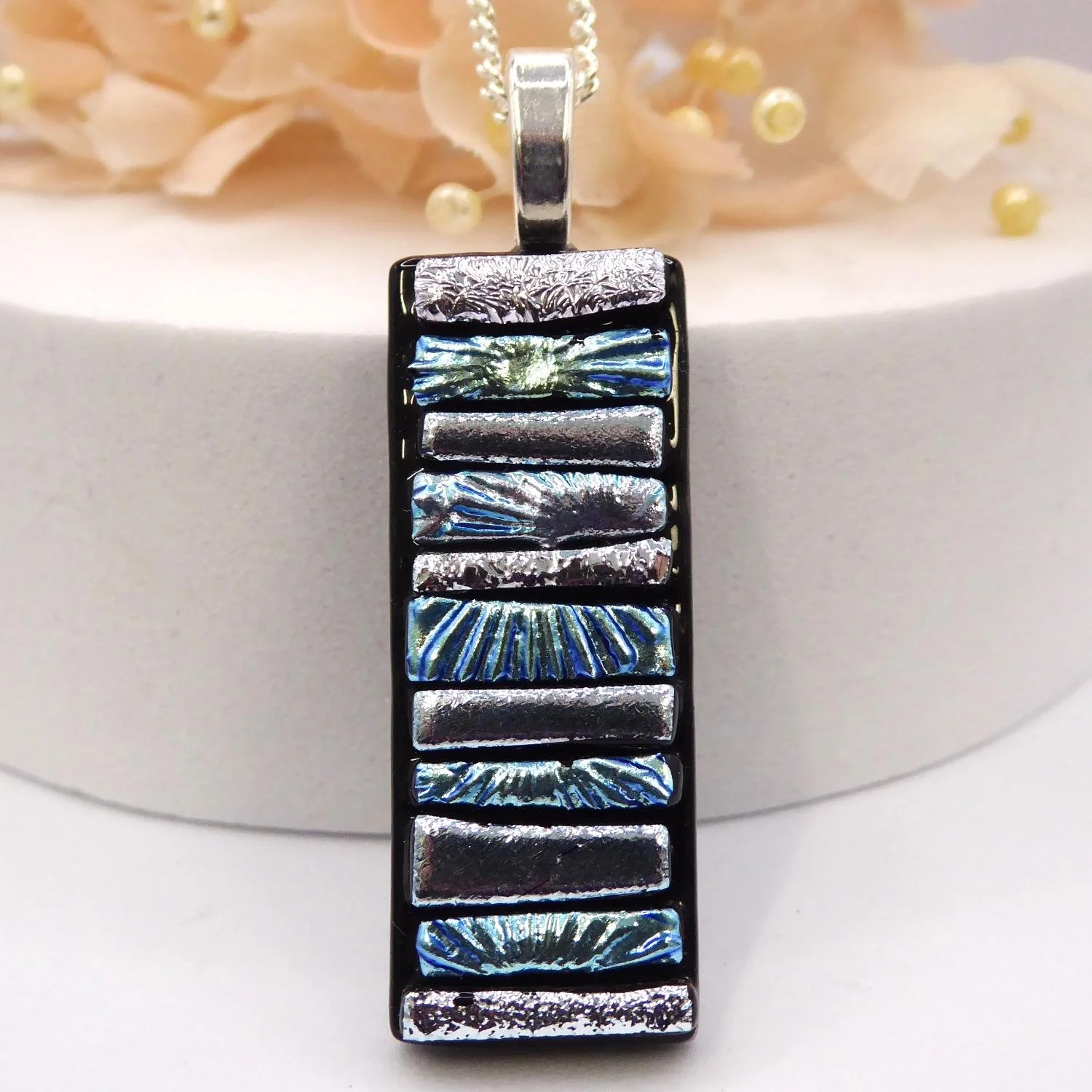  Silver fused glass pendant with strips of coloured and textured silver dichroic glass fired onto black glass. 