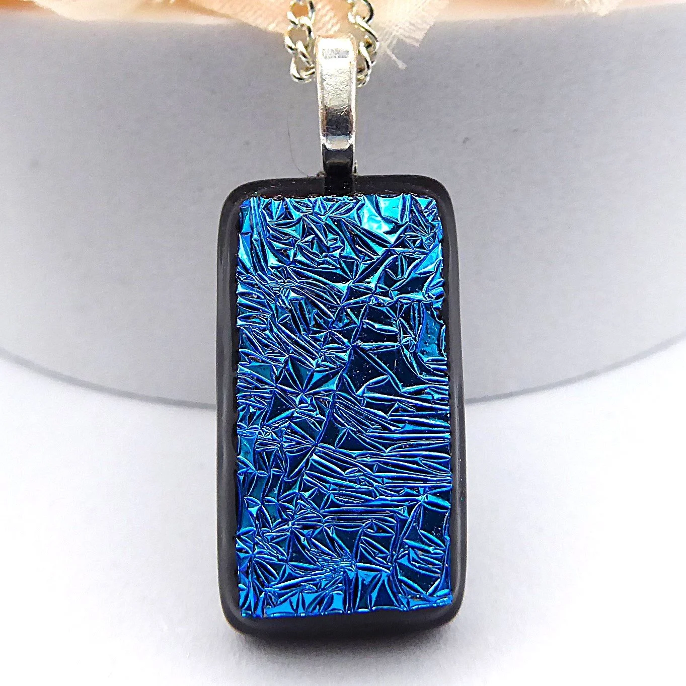  Fused glass pendant necklace with textured blue dichroic glass on a black background 