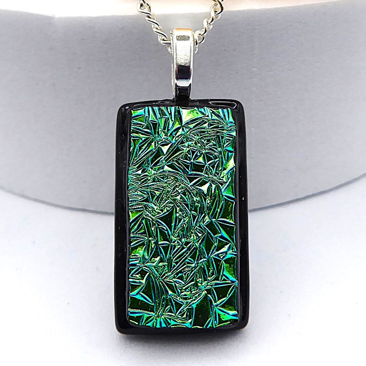  Fused glass pendant with textured green dichroic glass on a black background 