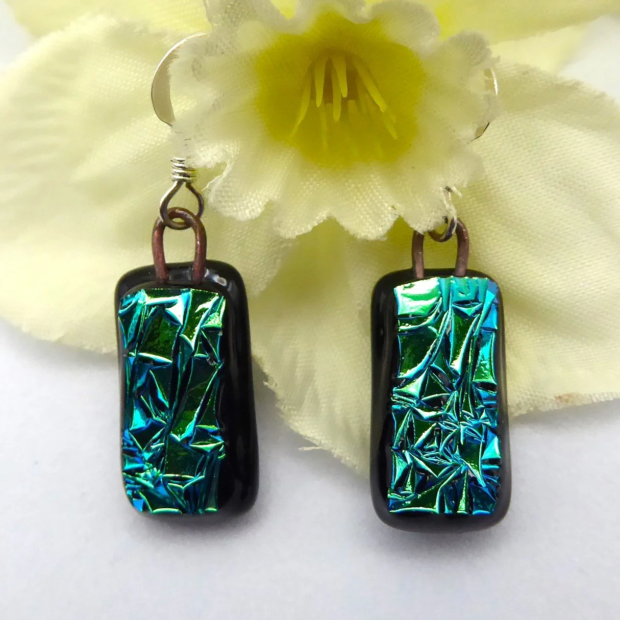  Fused glass earrings in a drop style with sparkling green textured dichroic glass on a black background 