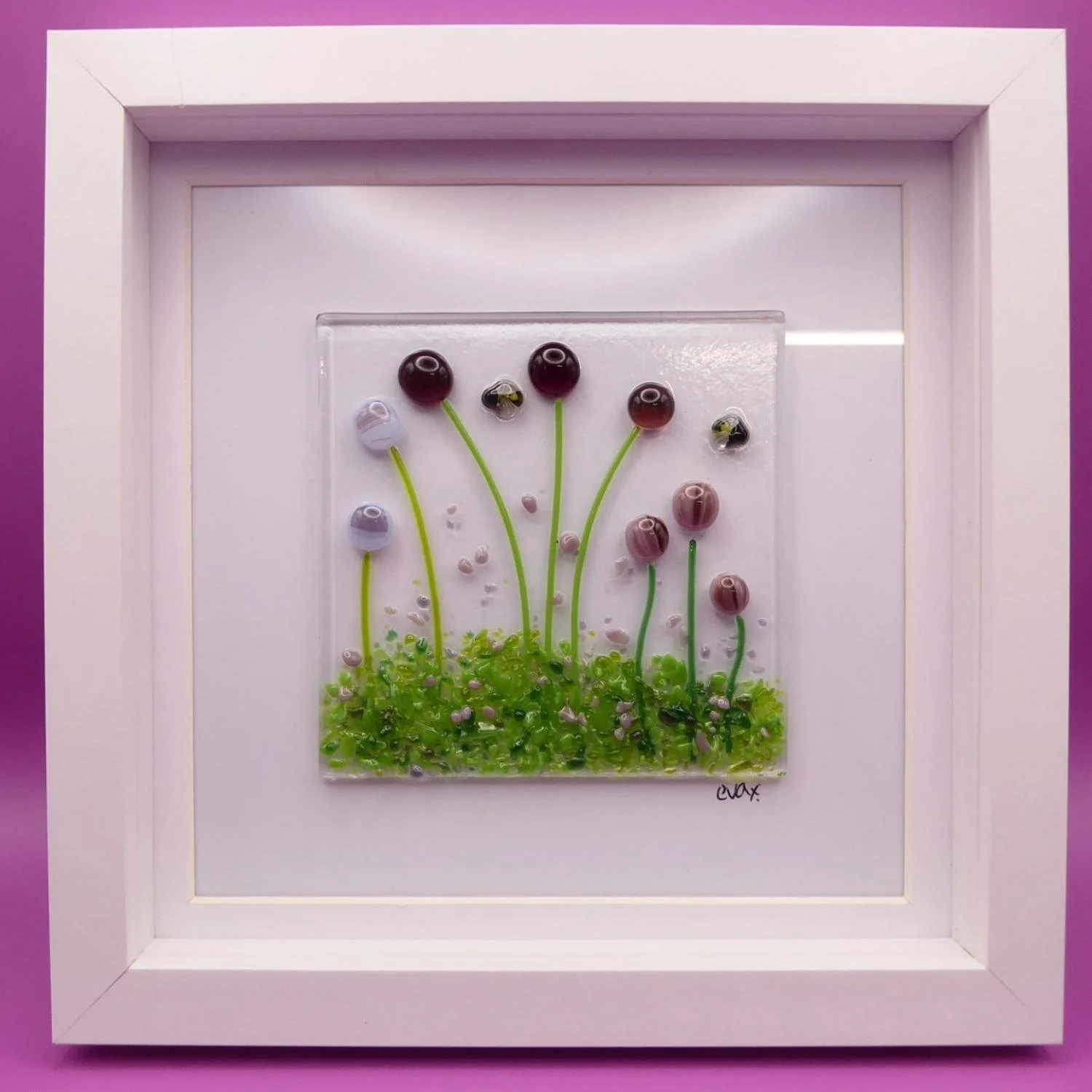  Framed fused glass floral-inspired artwork with pink and purple flowers and bees. 