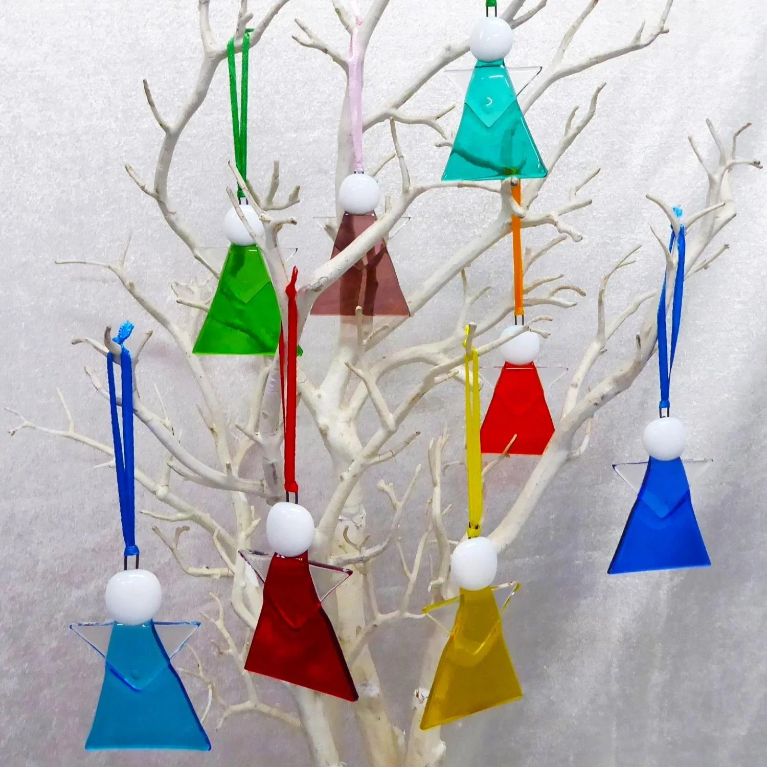  Colourful fused glass angels hanging on a Christmas tree 