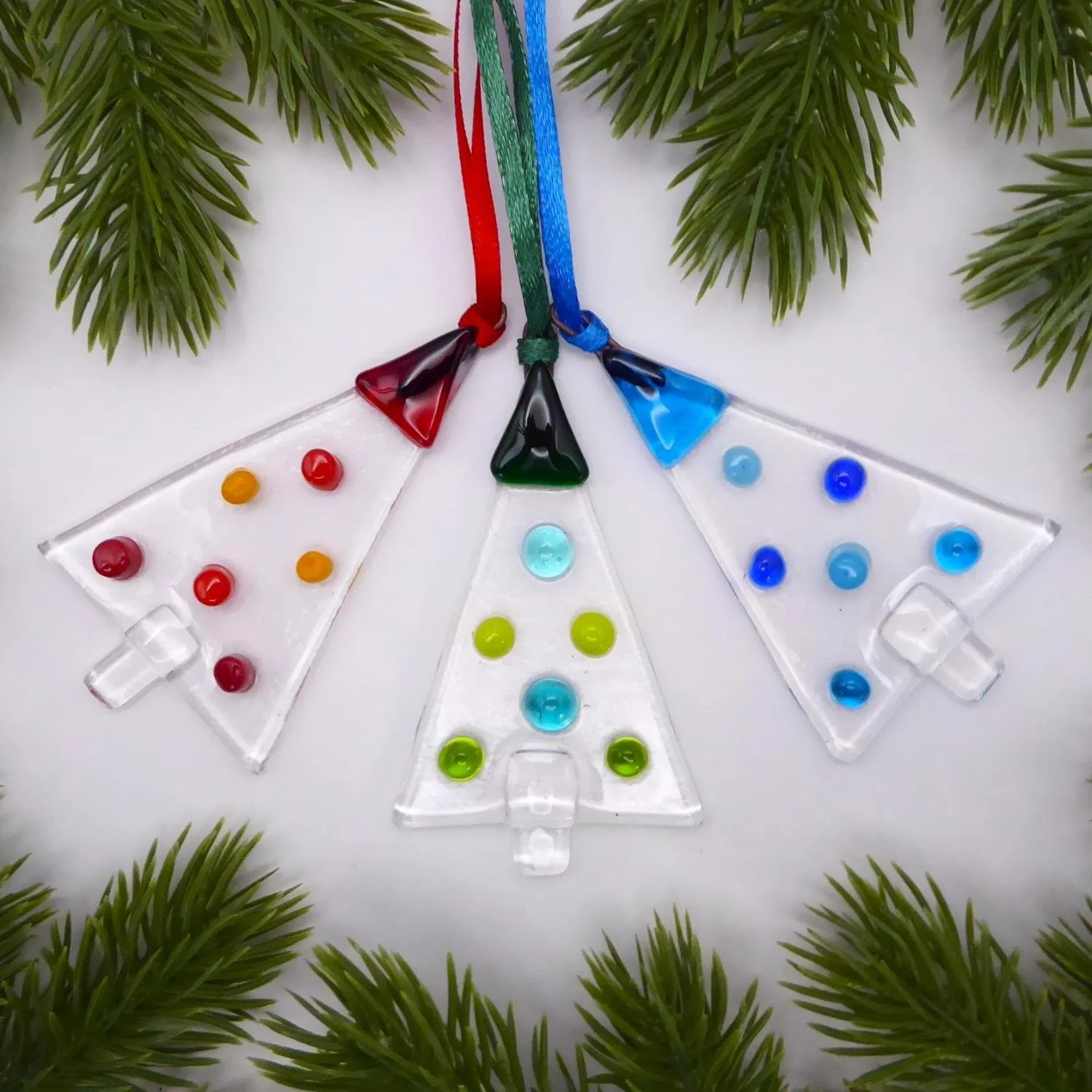 Fused glass Christmas trees with colourful glass baubles on a clear glass background. 