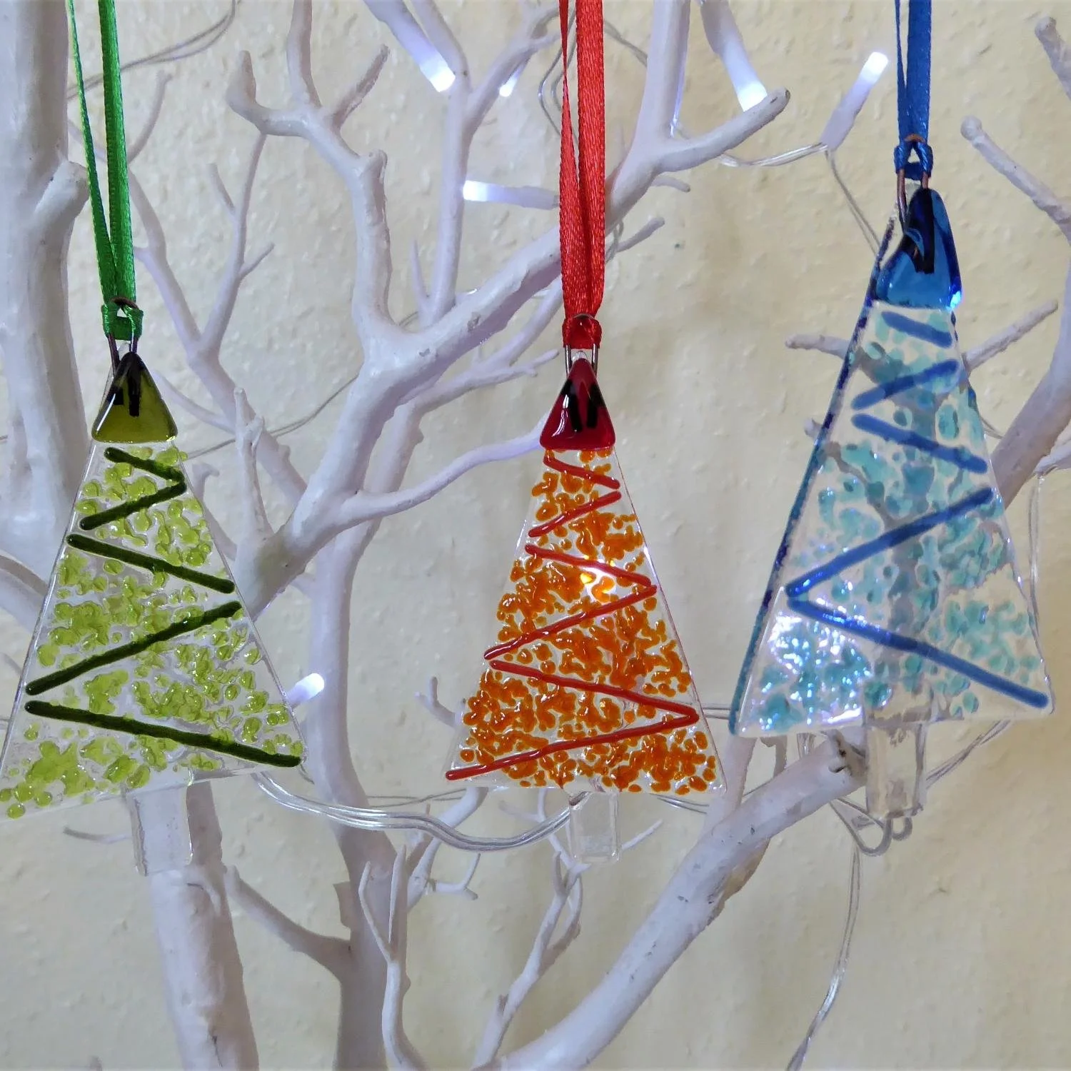  Hanging fused glass Christmas ornaments in tree shapes with designs representing tinsel on a tree 