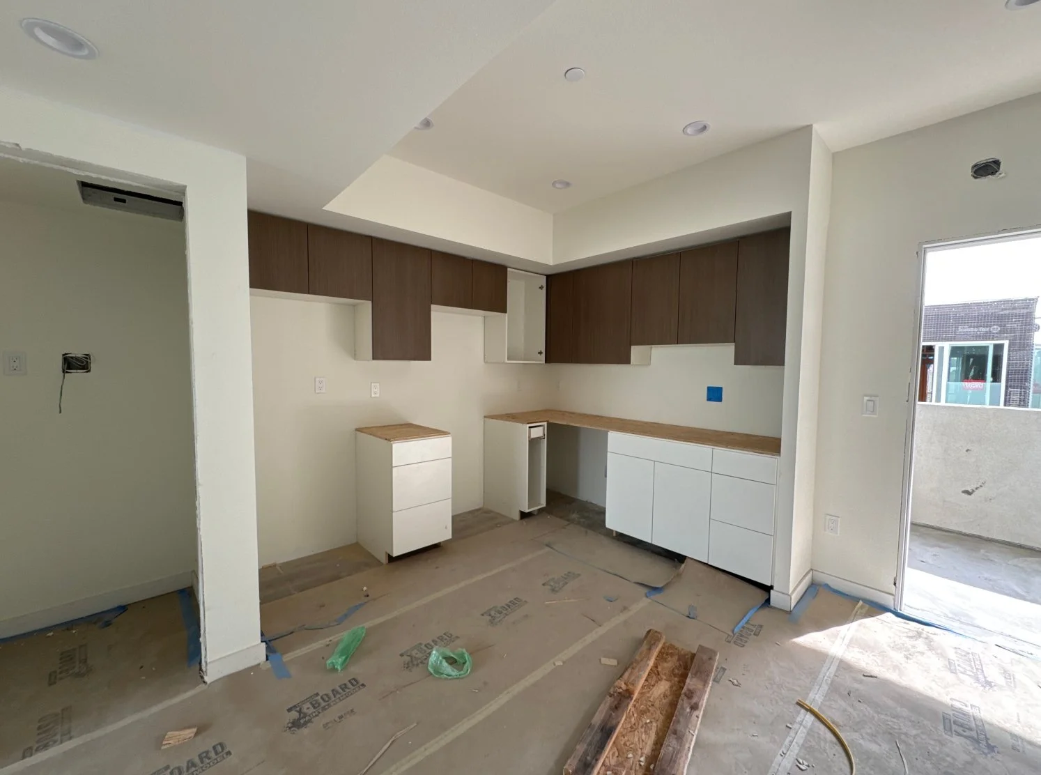 Kitchen under construction with upper cabinets, lower cabinets, and a countertop installed, but appliances are not yet in place.