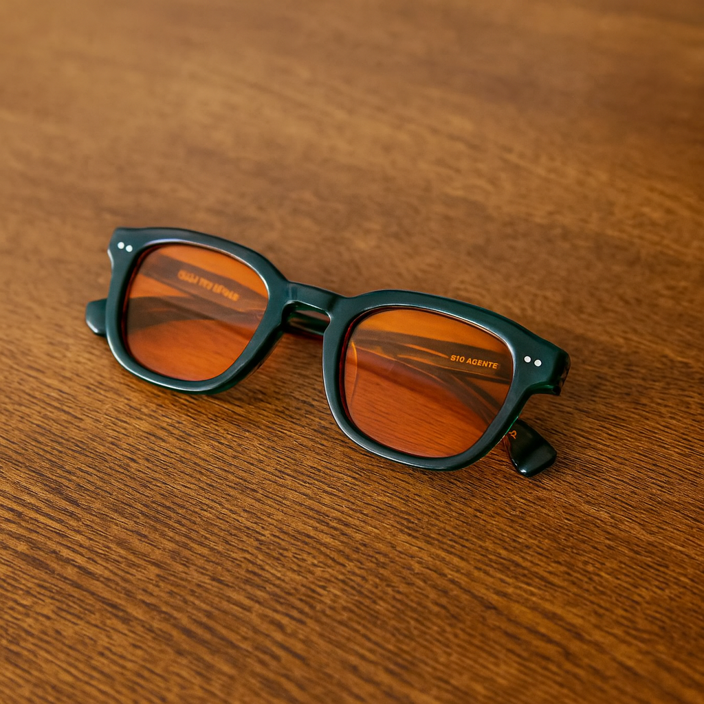 Pair of black sunglasses with orange tinted lenses placed on a wooden surface.