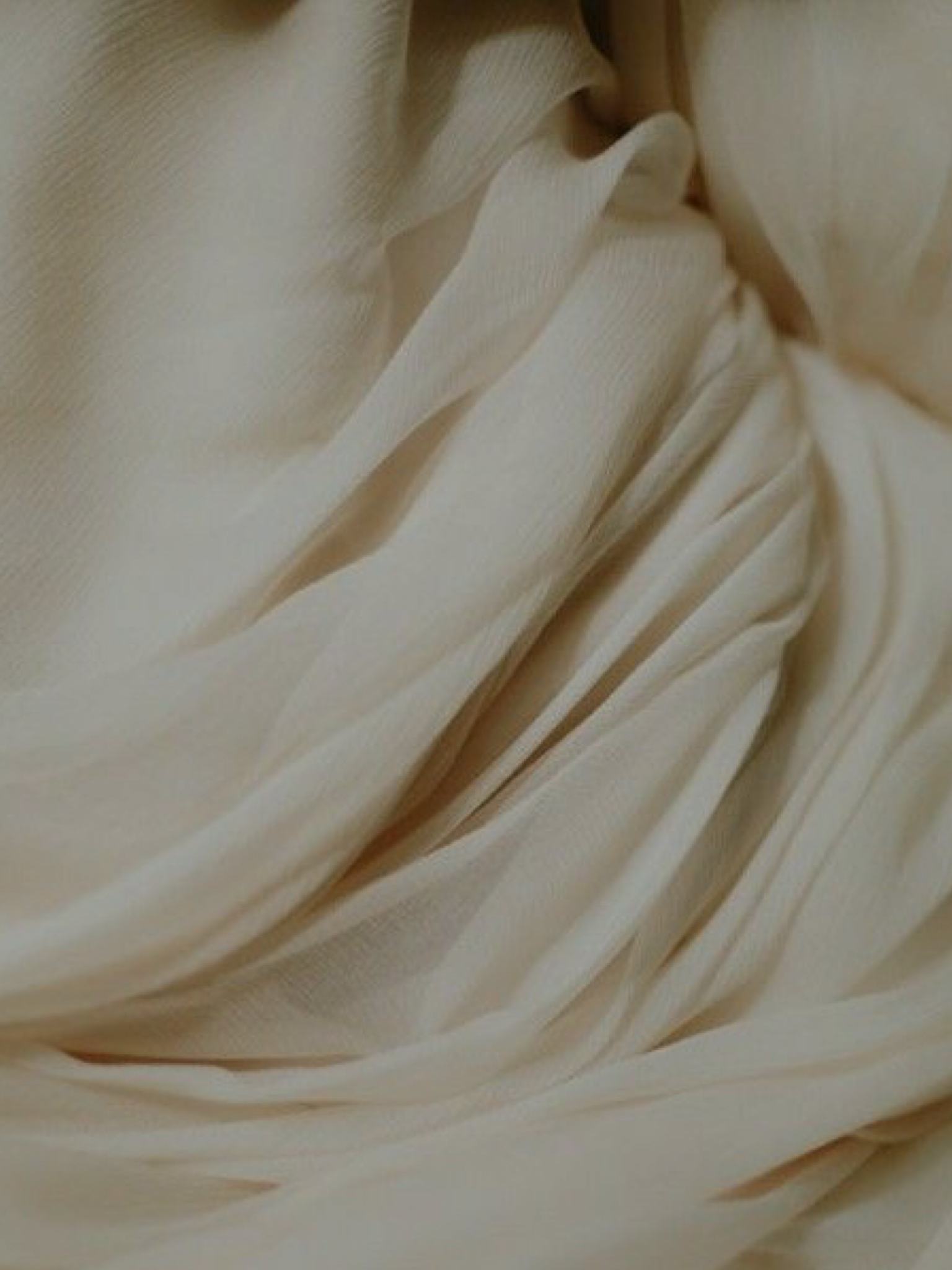 Close-up of cream-colored fabric with soft folds and texture.