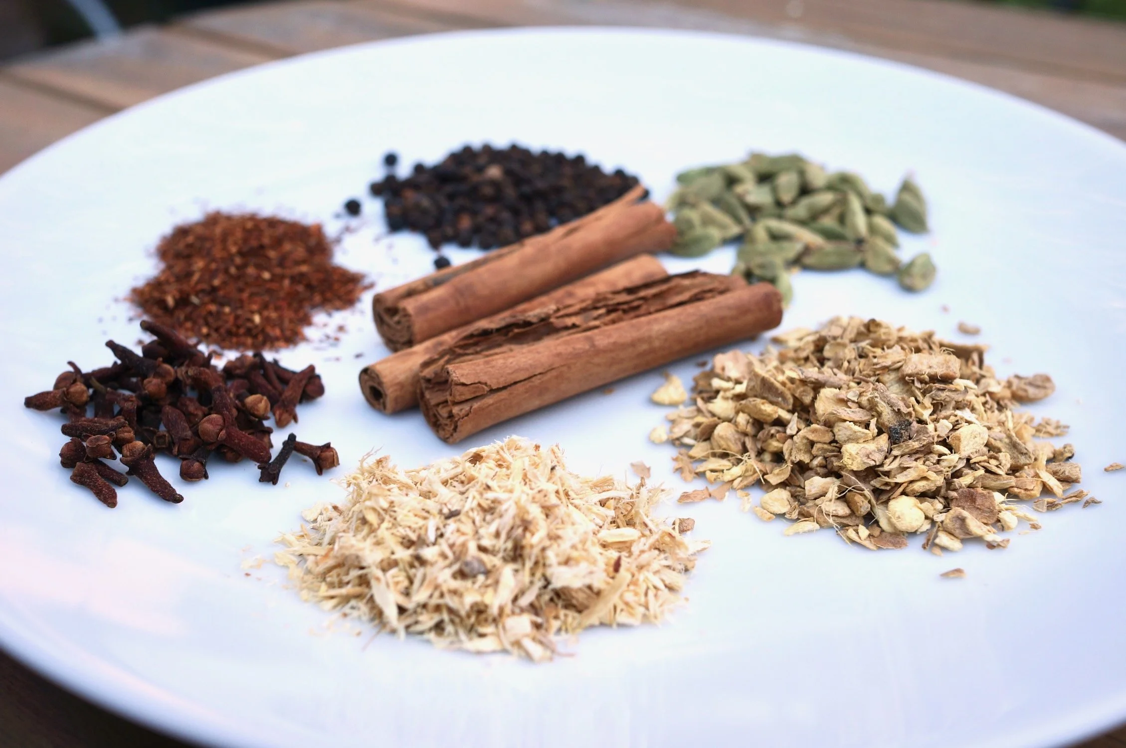 various medicinal and culinary barks, roots and spices in small piles on a plate