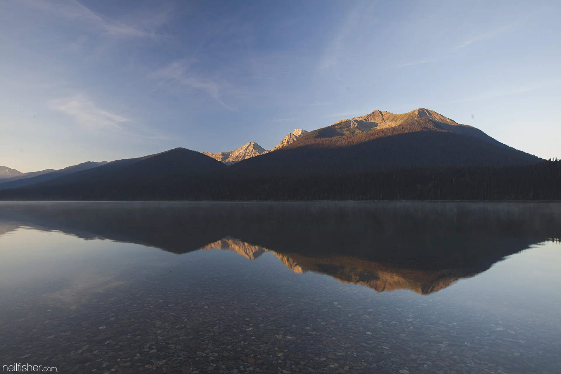 As the sun crawls above the horizon Mount Peever is slowly painted with a great orange hue. The perfectly clear water of Isaac reveal the millions of smooth pebbles that line the shore. The warm lake water mixing with the cool morning air create an eerie mist that creeps across the surface. EXIF 0.4sec f/9.0 ISO50 21mm