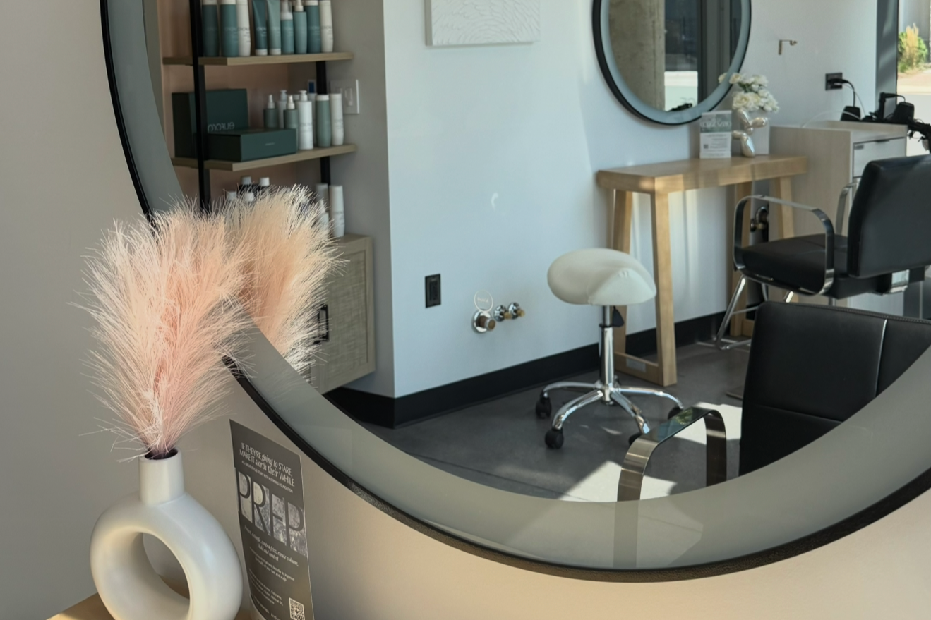 Bright, modern salon suite at Divine Beauty Lab featuring a styling station, round mirror, product display, and contemporary décor in Chicago’s River North neighborhood.
