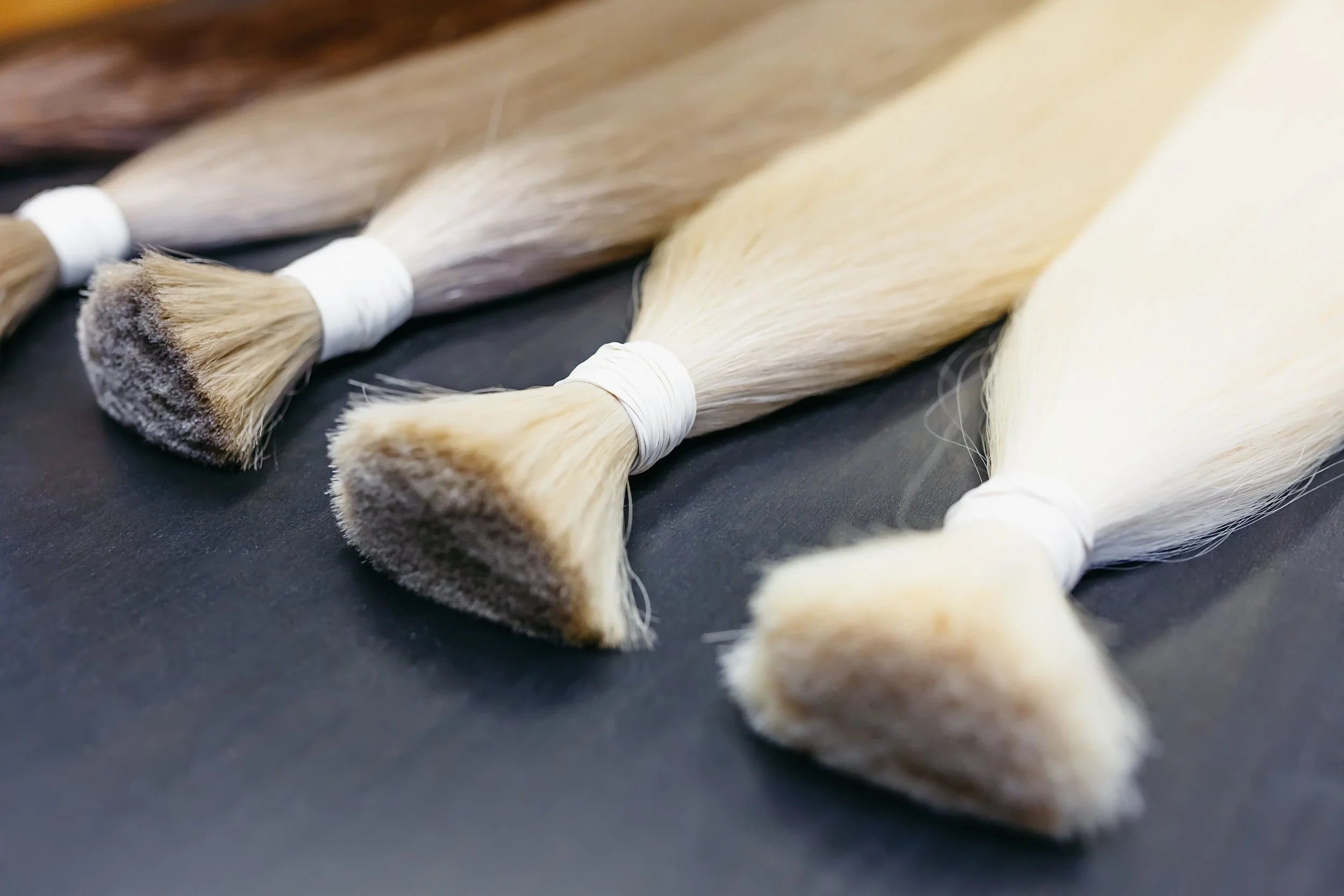 Wefts of hair laying on a table bundled with rubber bands