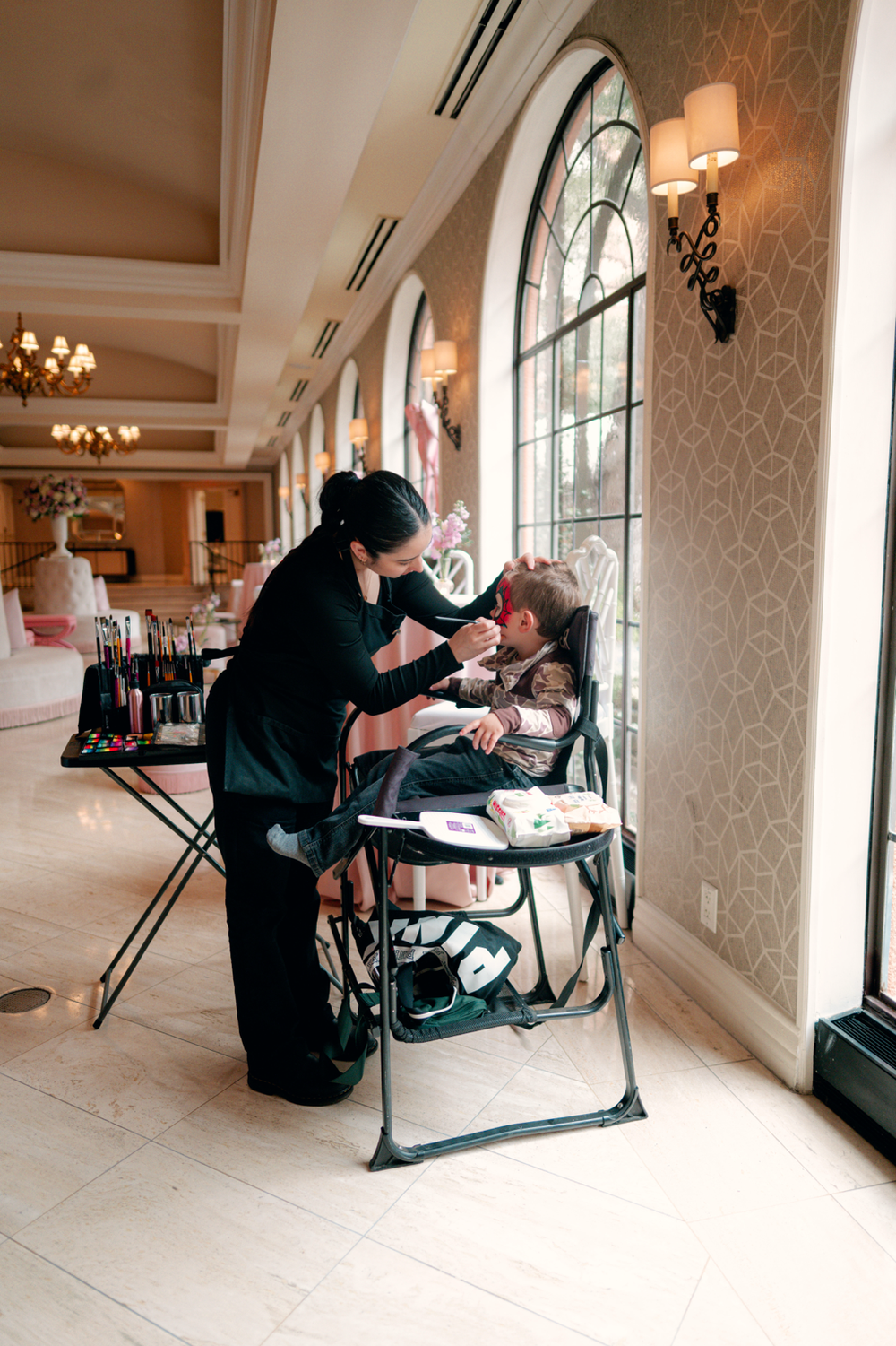 Judy face painting a child at an indoor event