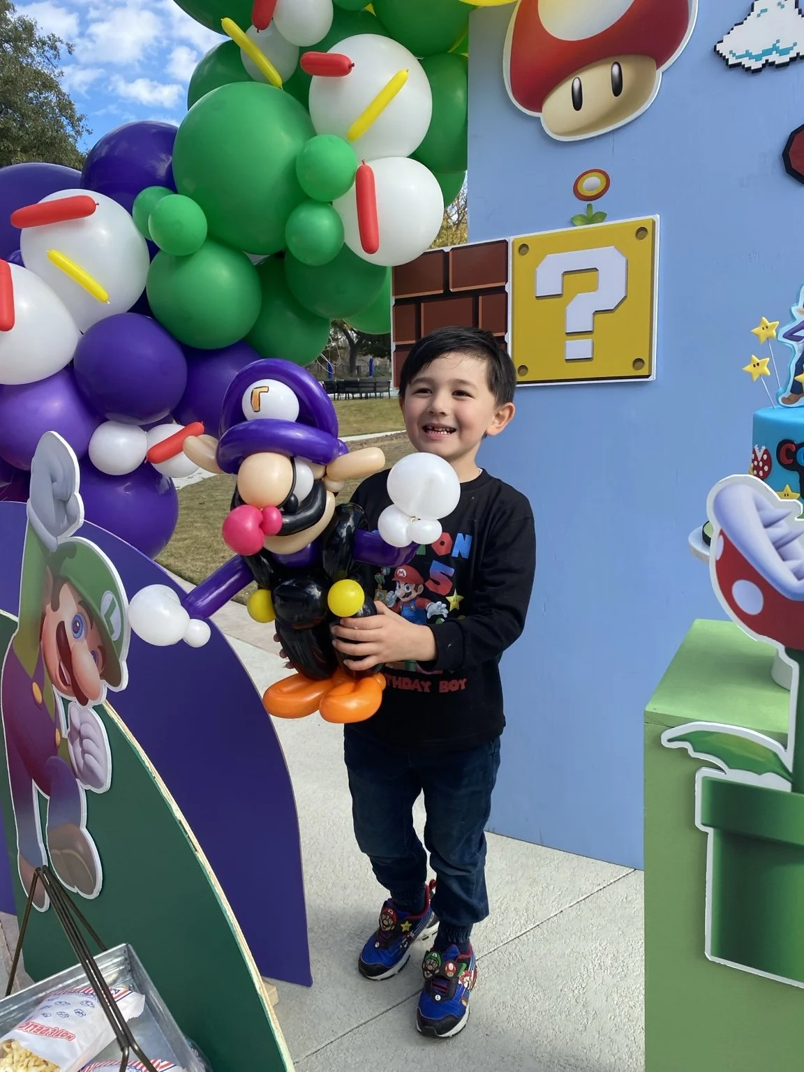 Smiling child holding a Super Mario balloon creation