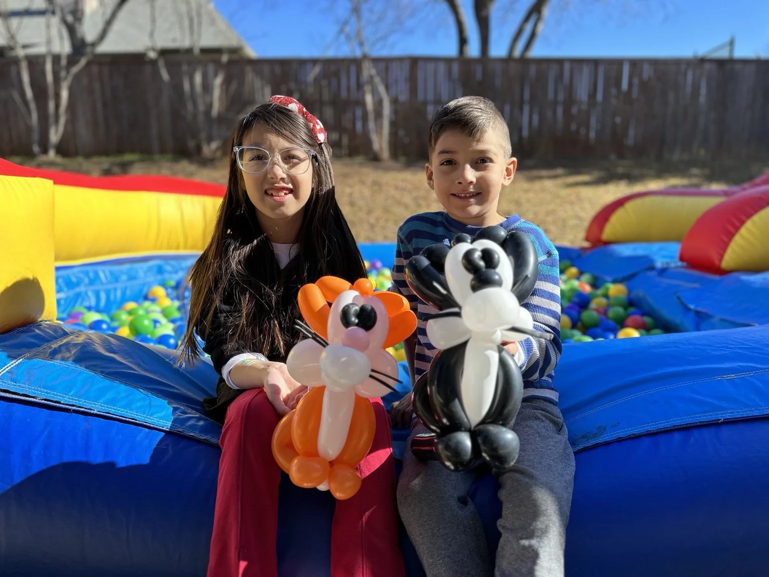 Children holding fox and panda balloon animals