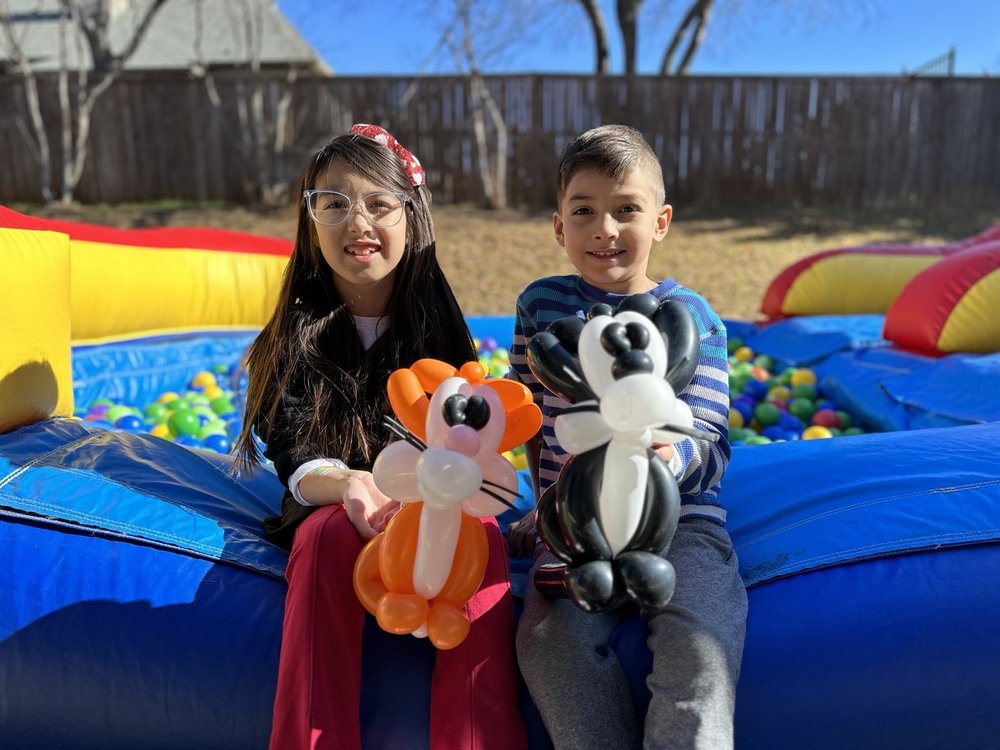 Children holding fox and panda balloon animals