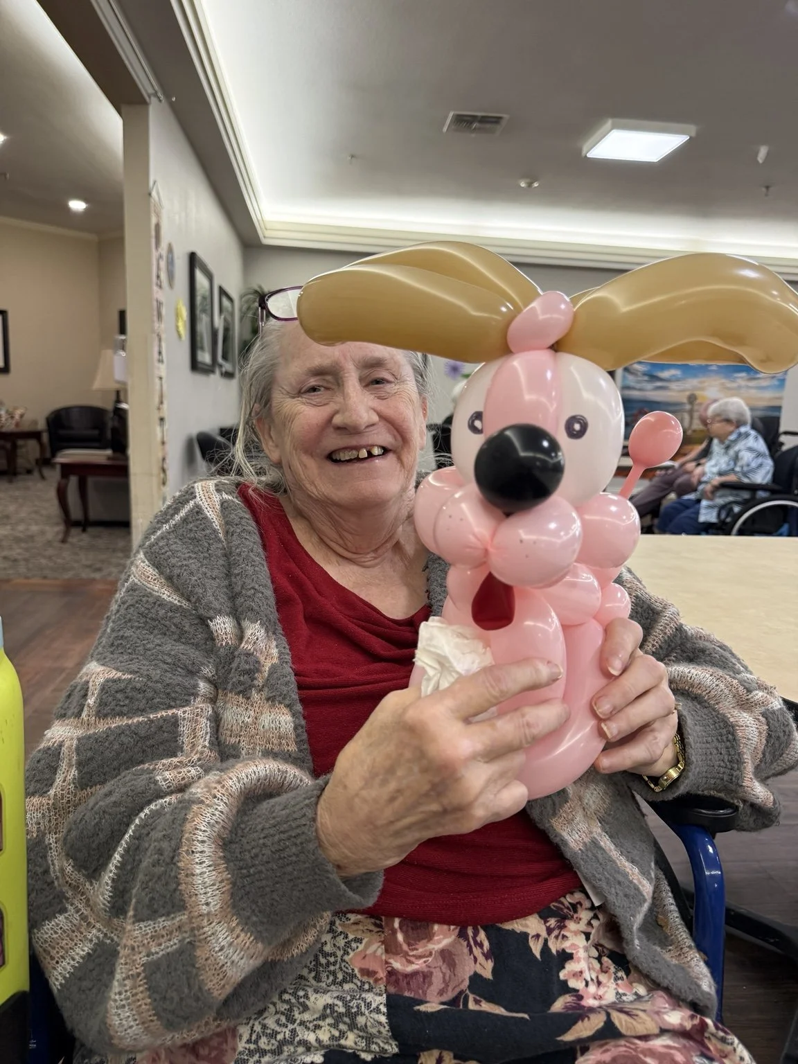 Woman holding a pink balloon dog at an indoor event