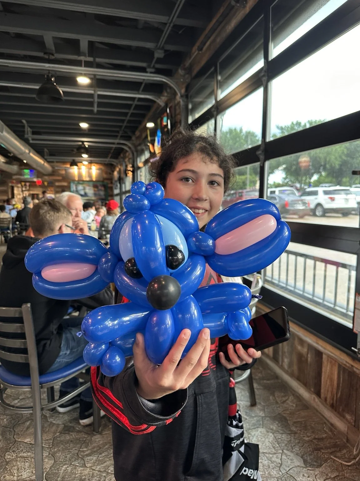 Child holding a blue balloon dog