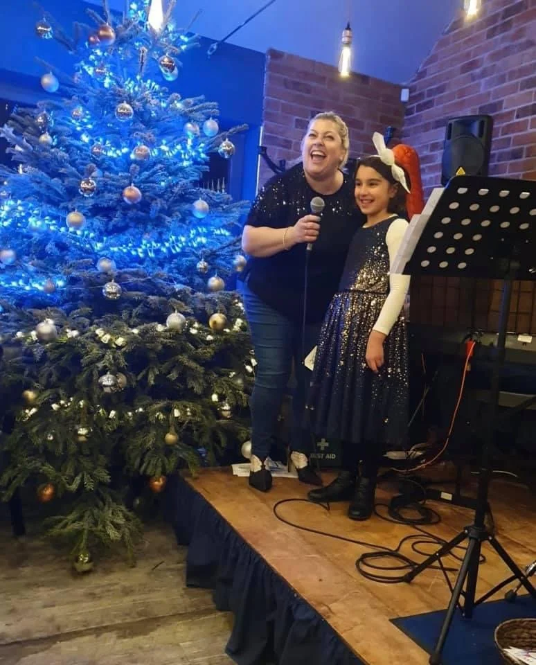 Lady in a Santa hat and a young girl are singing