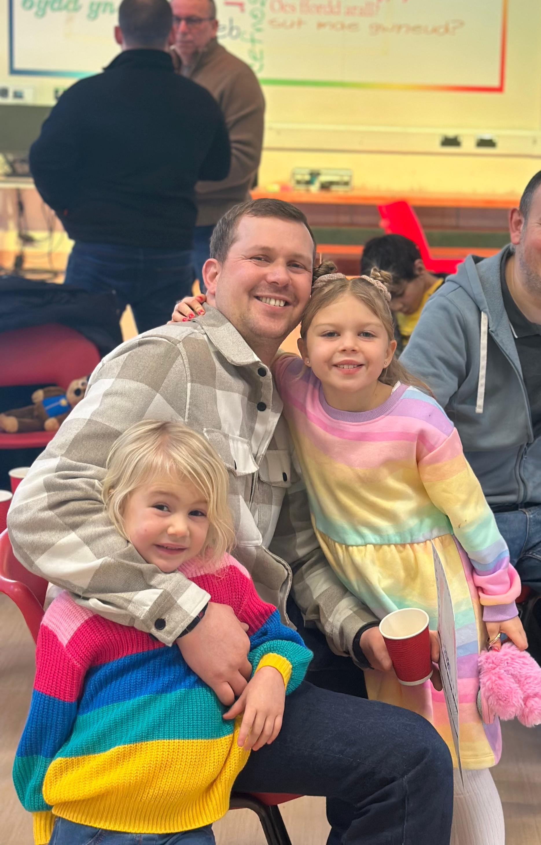 Man smiles with his two young daughters at church